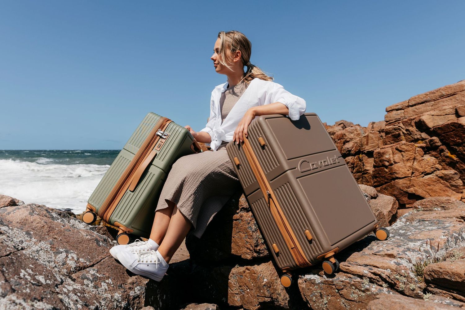 Vintage suitcases positioned on rocky coastal landscape with ocean view.