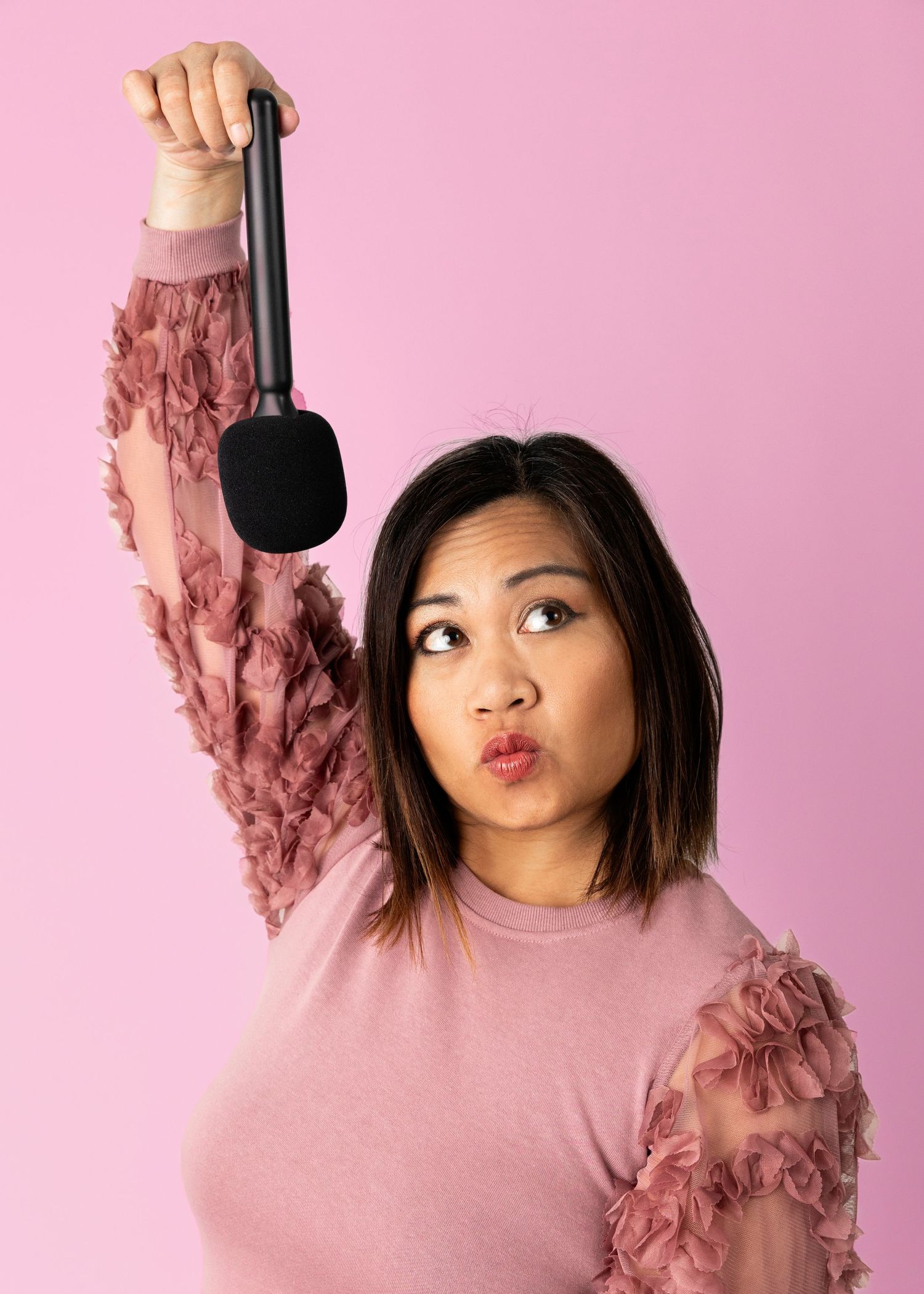 Pink sweater with ruffled details against pastel pink background.