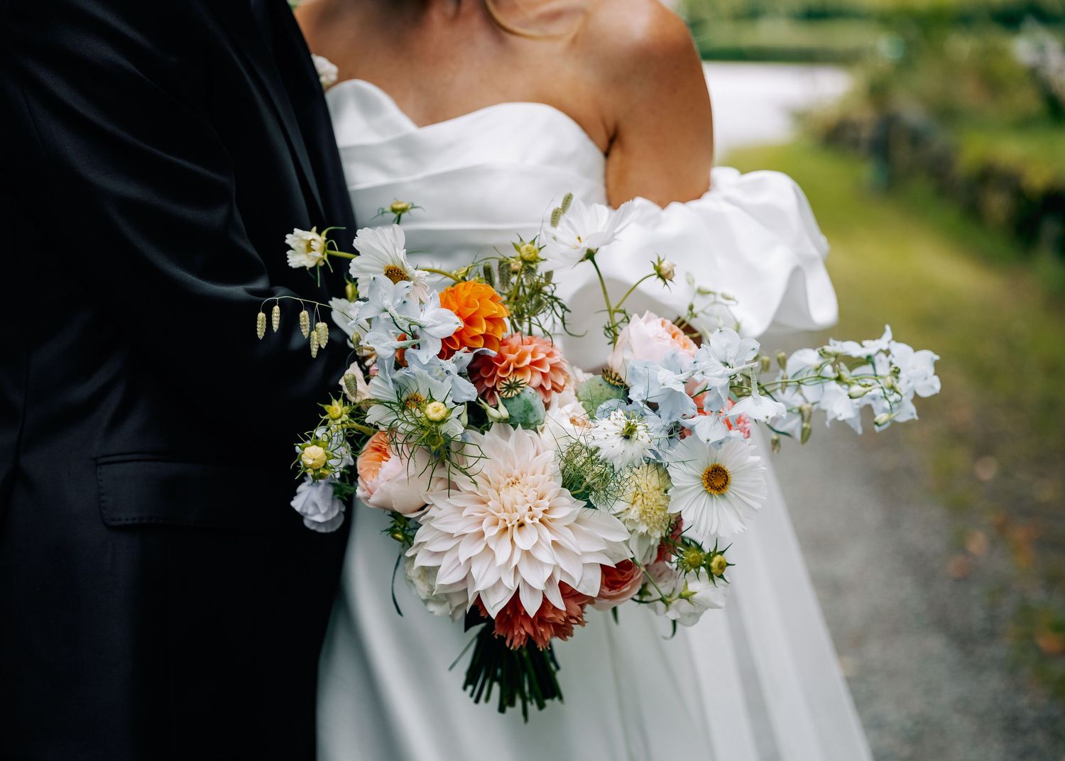 Wedding couple embracing with colorful floral bouquet in foreground.