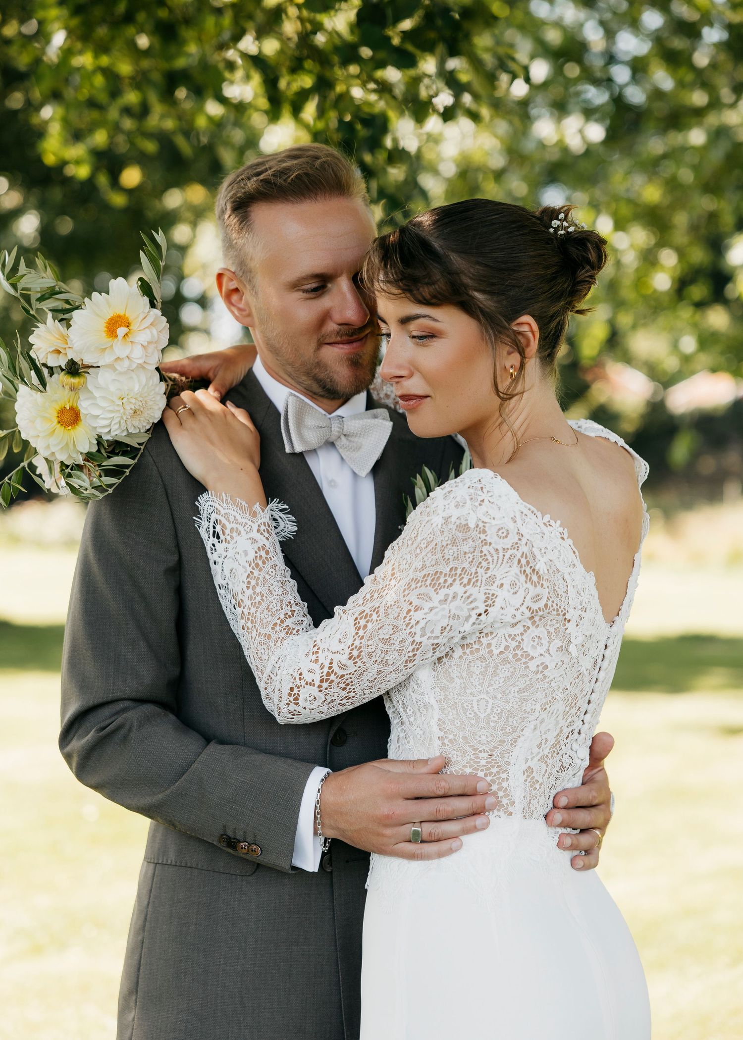 Romantic wedding portraits under trees with lace dress details and soft natural lighting.