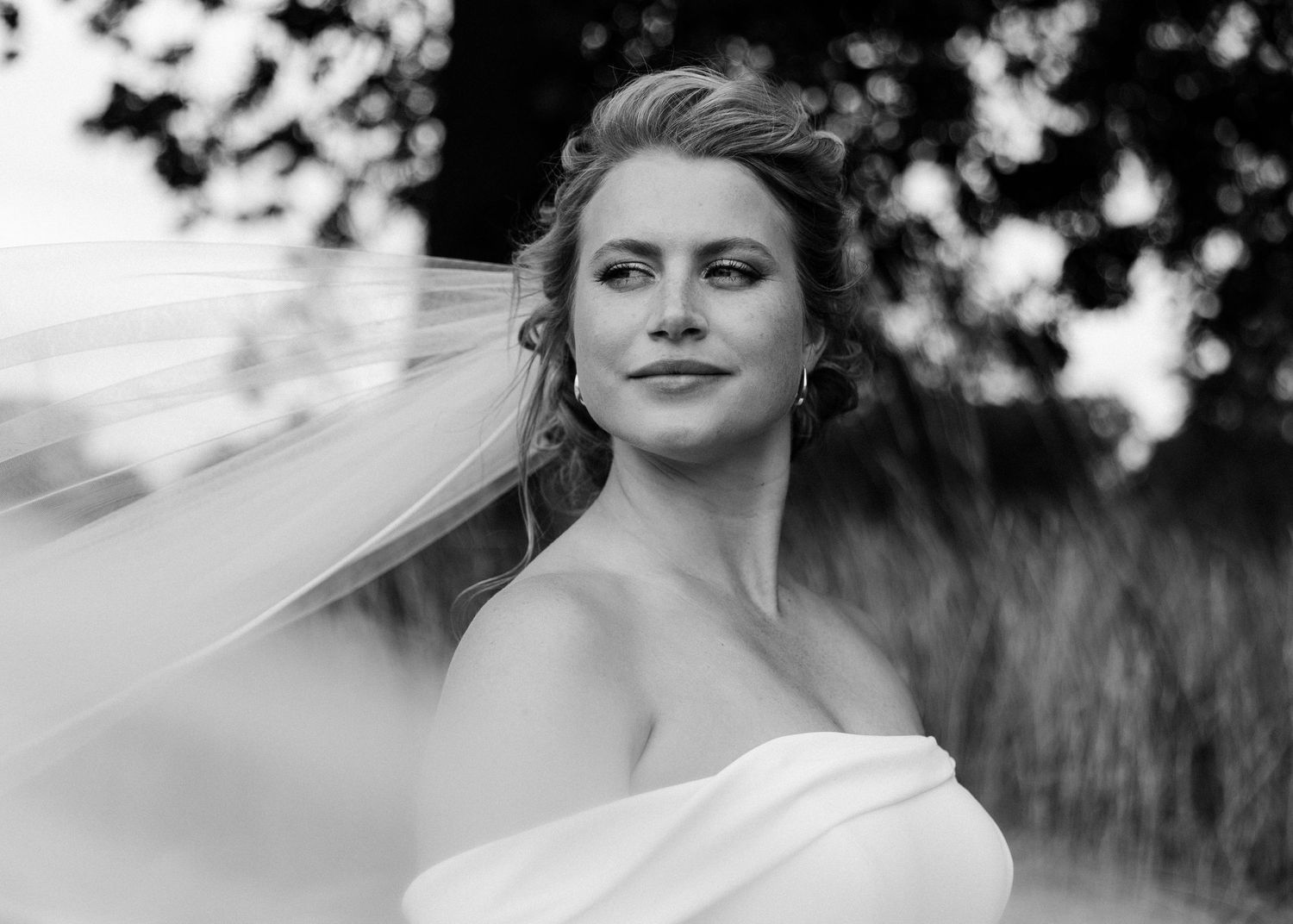 Black and white bridal portrait with veil flowing in the wind.