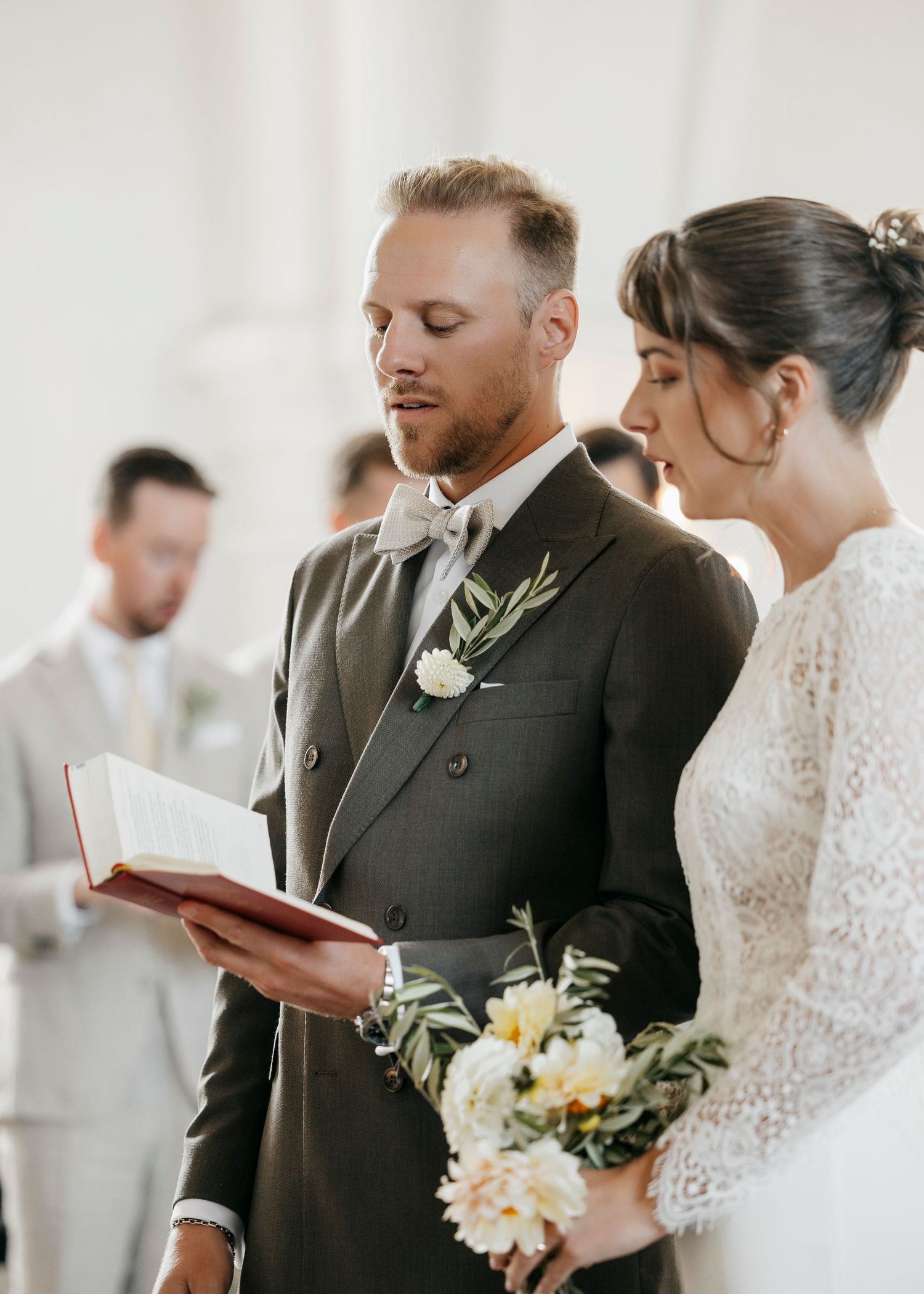 Intimate wedding ceremony moment in a bright church with floral decorations.