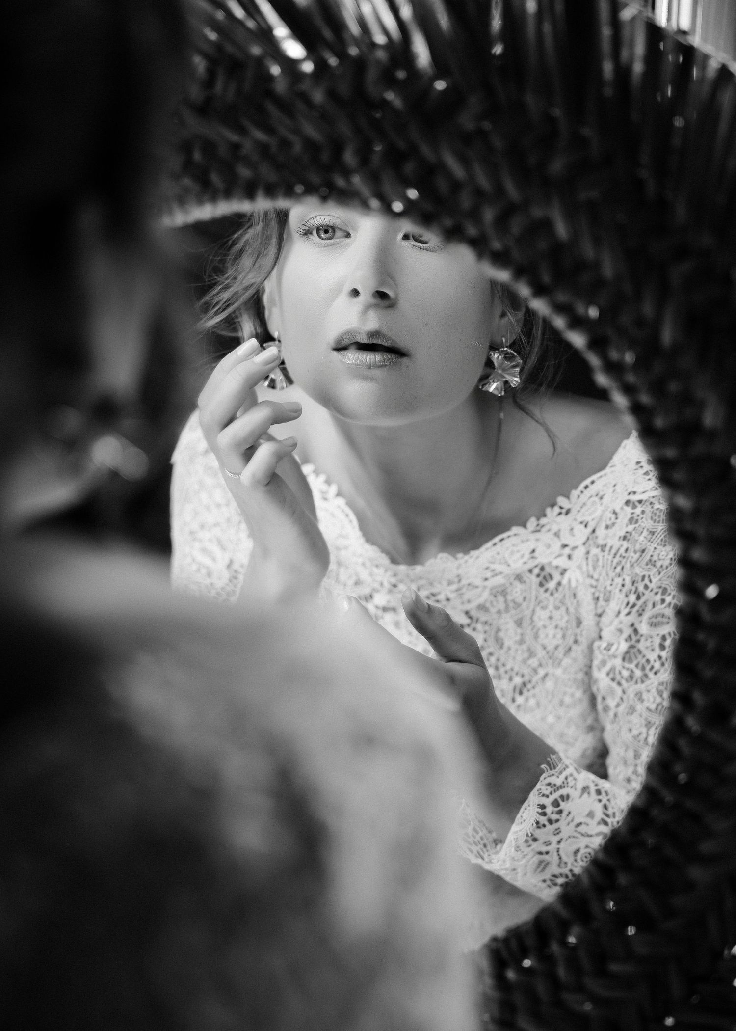 A black and white portrait through a mirror showing a woman in lace wearing elegant earrings.