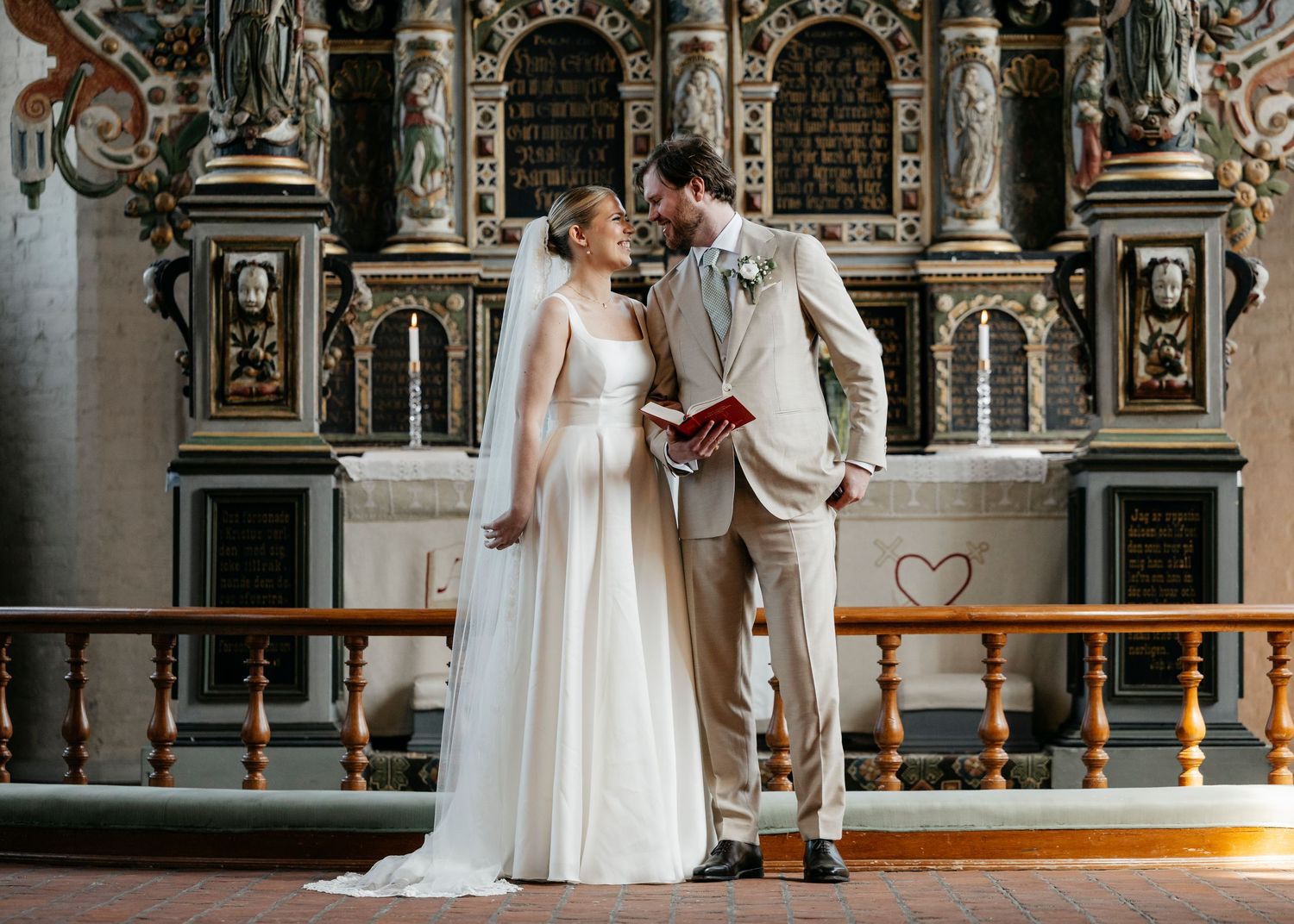 Couple shares intimate moment in ornate church setting with elegant wedding attire and traditional architecture.