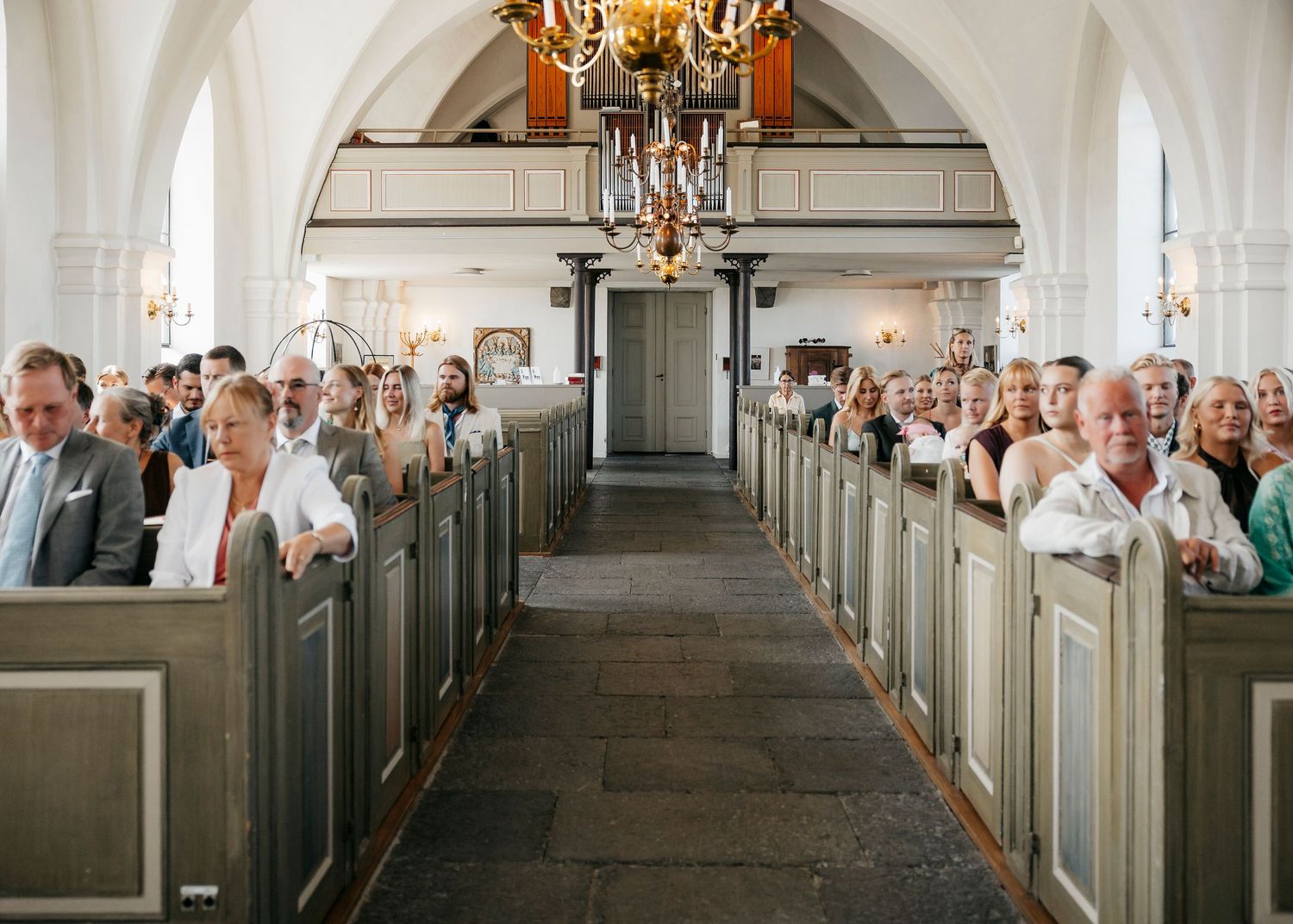 Panoramic view of church interior with rows of pews and vaulted ceiling.