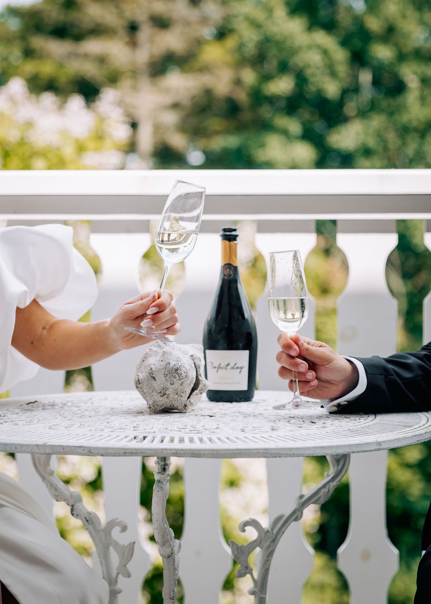Wedding reception details with wine glasses and place settings on white railing outdoors.