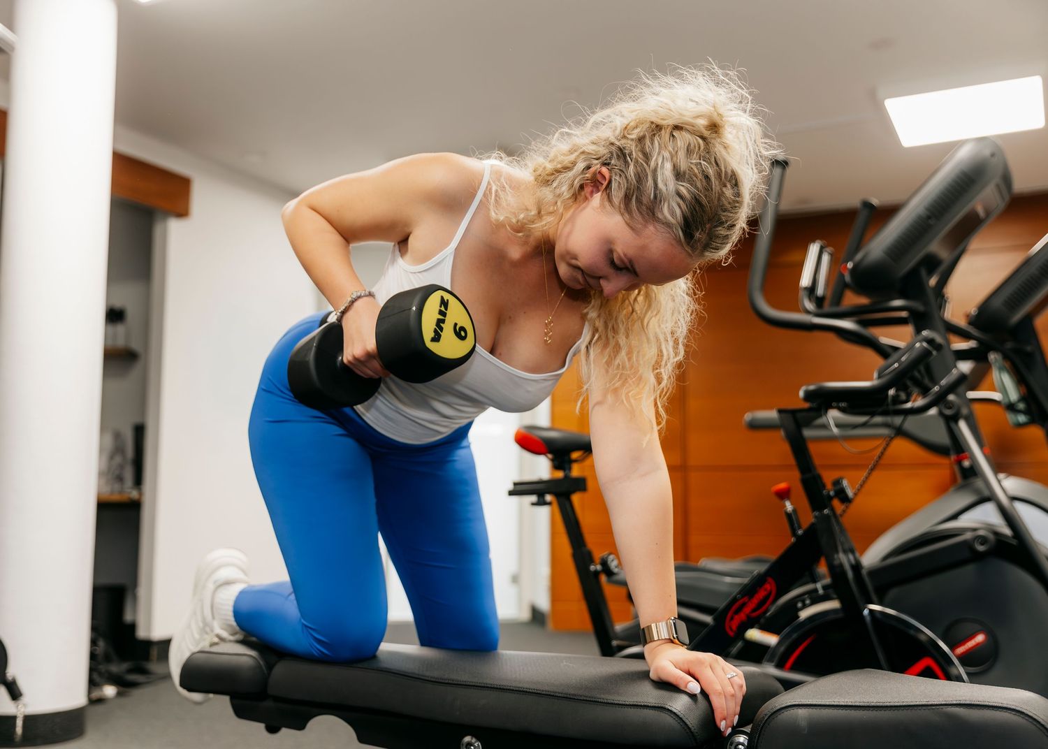Athletes exercising on fitness equipment in a modern gym setting.