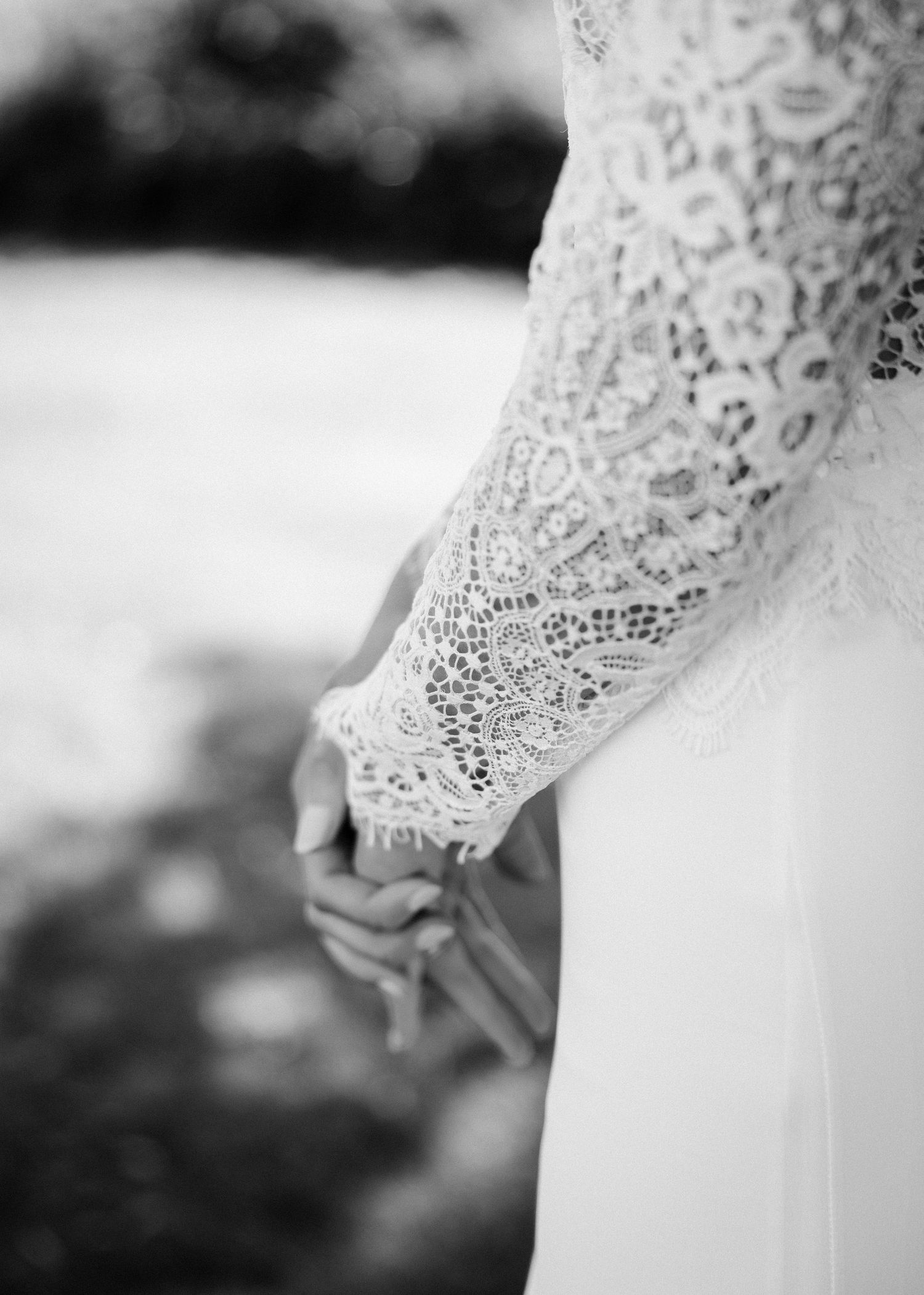 Close-up details of delicate lace sleeves on white wedding gown.