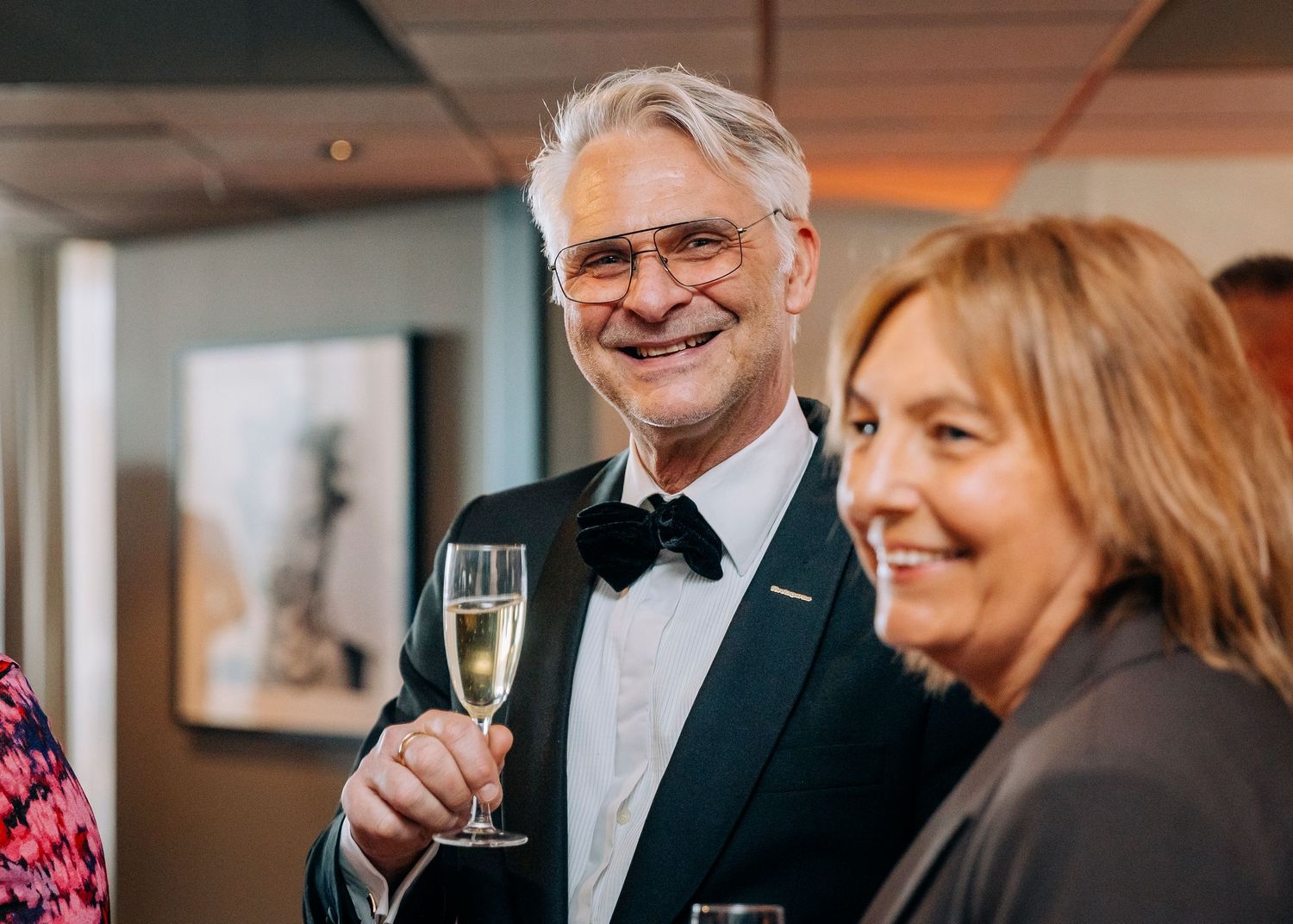 Formal gathering with guests in evening attire enjoying champagne and conversation.