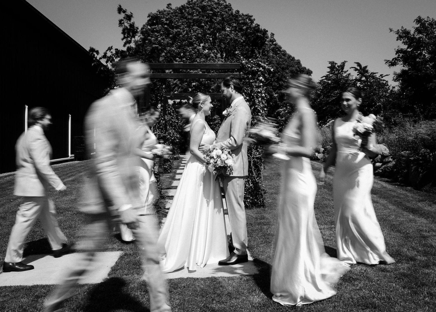 Motion-blur wedding party photo in black and white with central focus on ceremony.