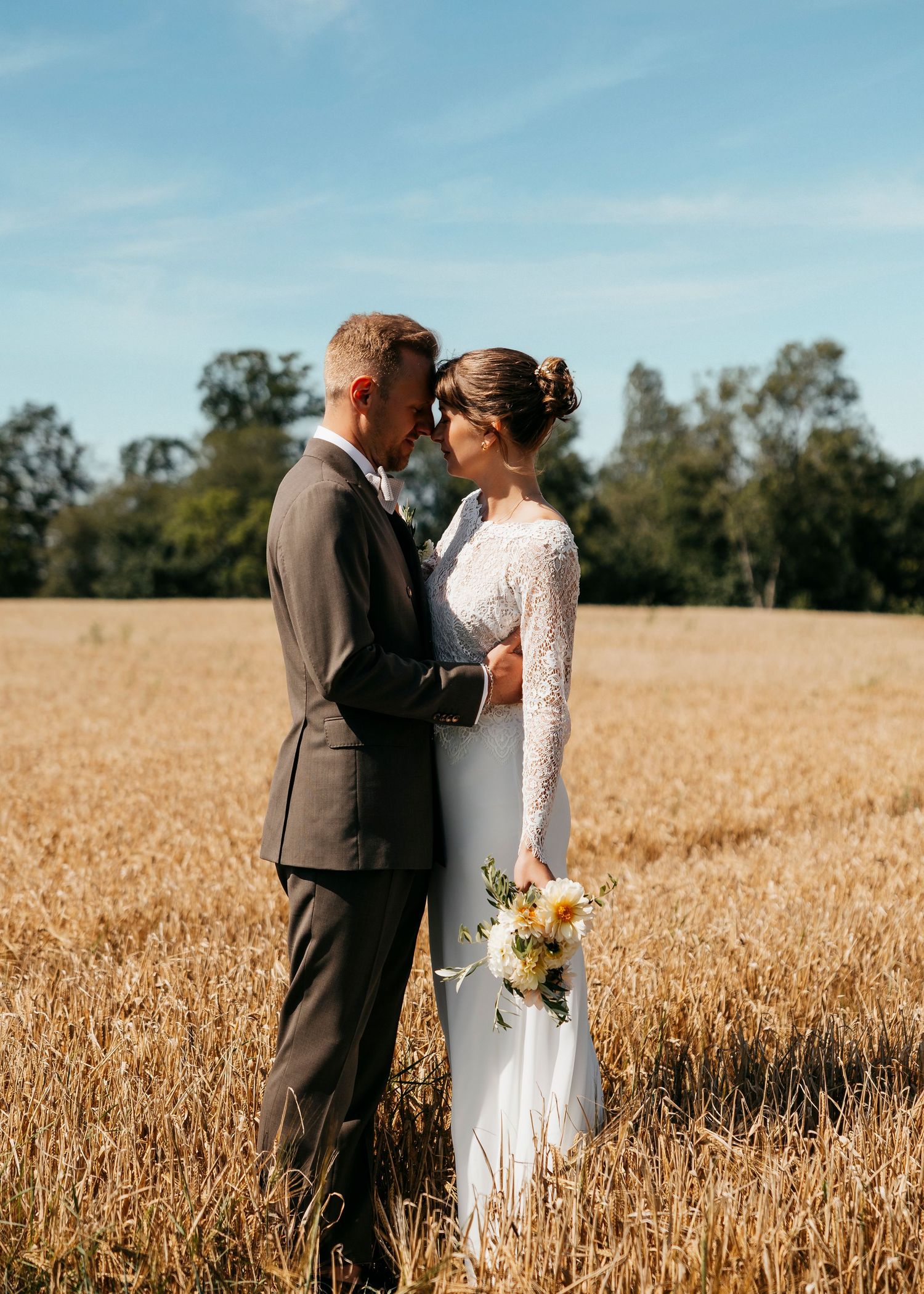 Wedding portraits captured in a scenic wheat field on a bright sunny day.