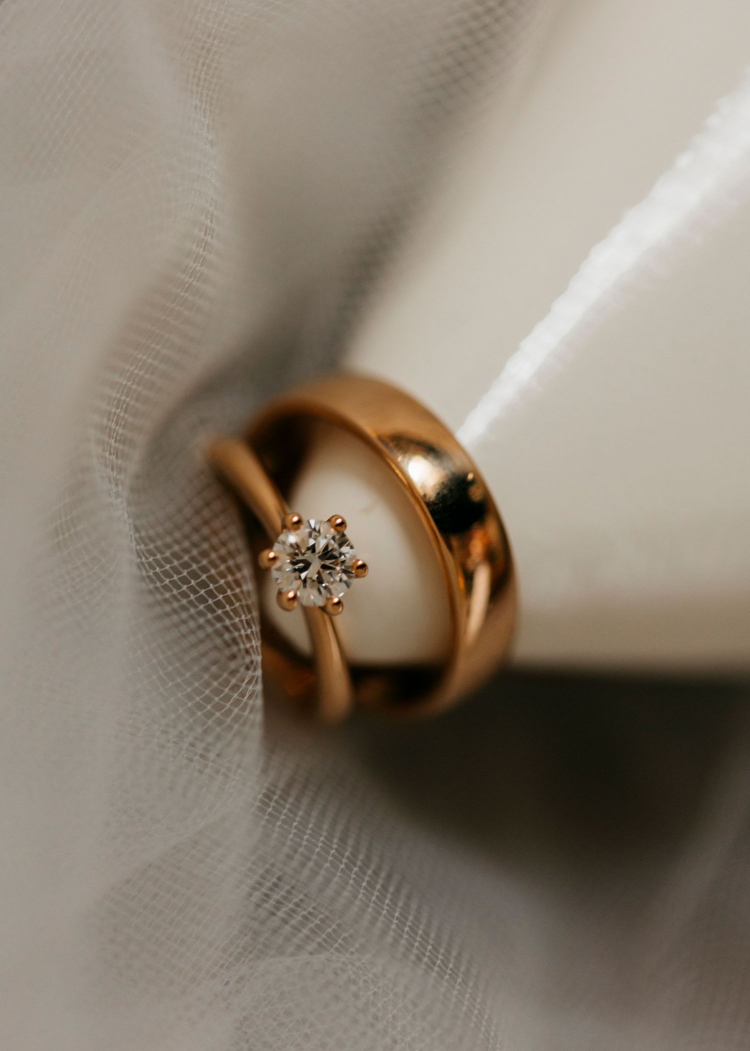 Close-up of gold wedding rings with diamond detail on white textured surface.