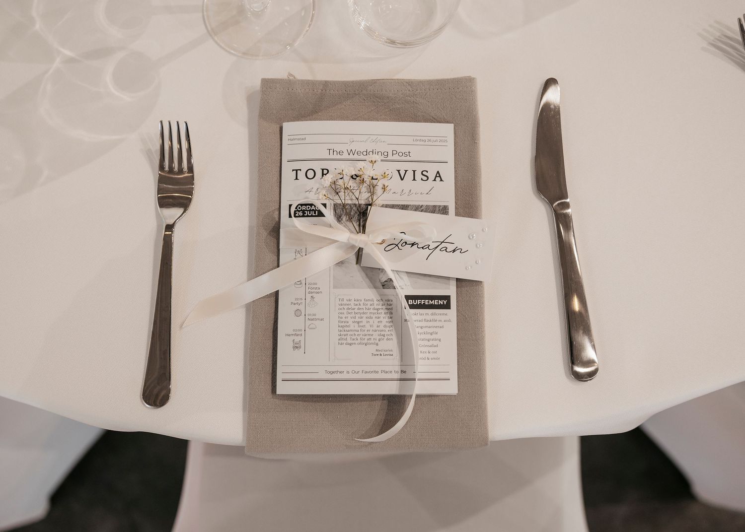 Place settings with formal silverware and menu cards at wedding reception.