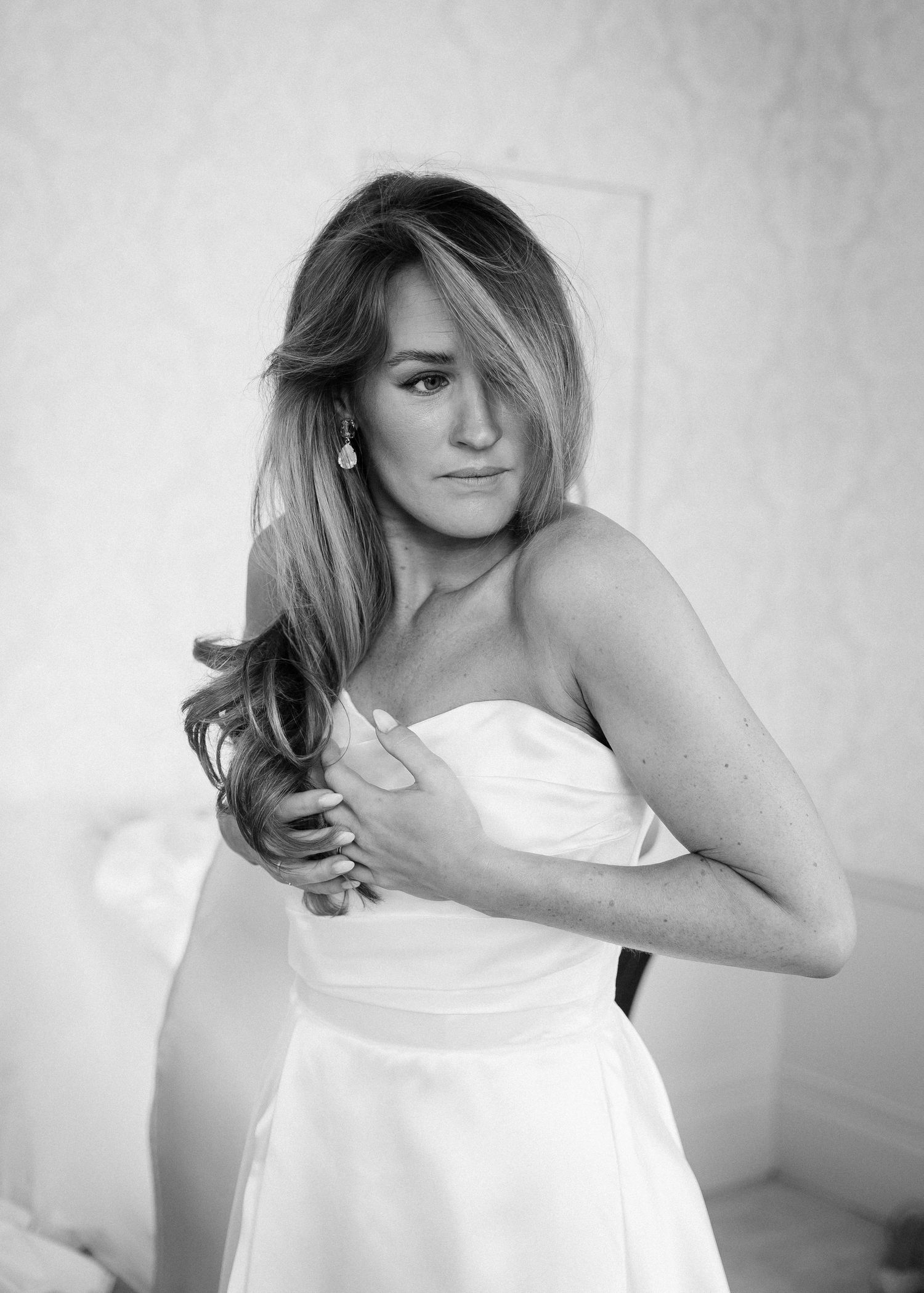 Elegant black and white portrait of person in strapless white dress.