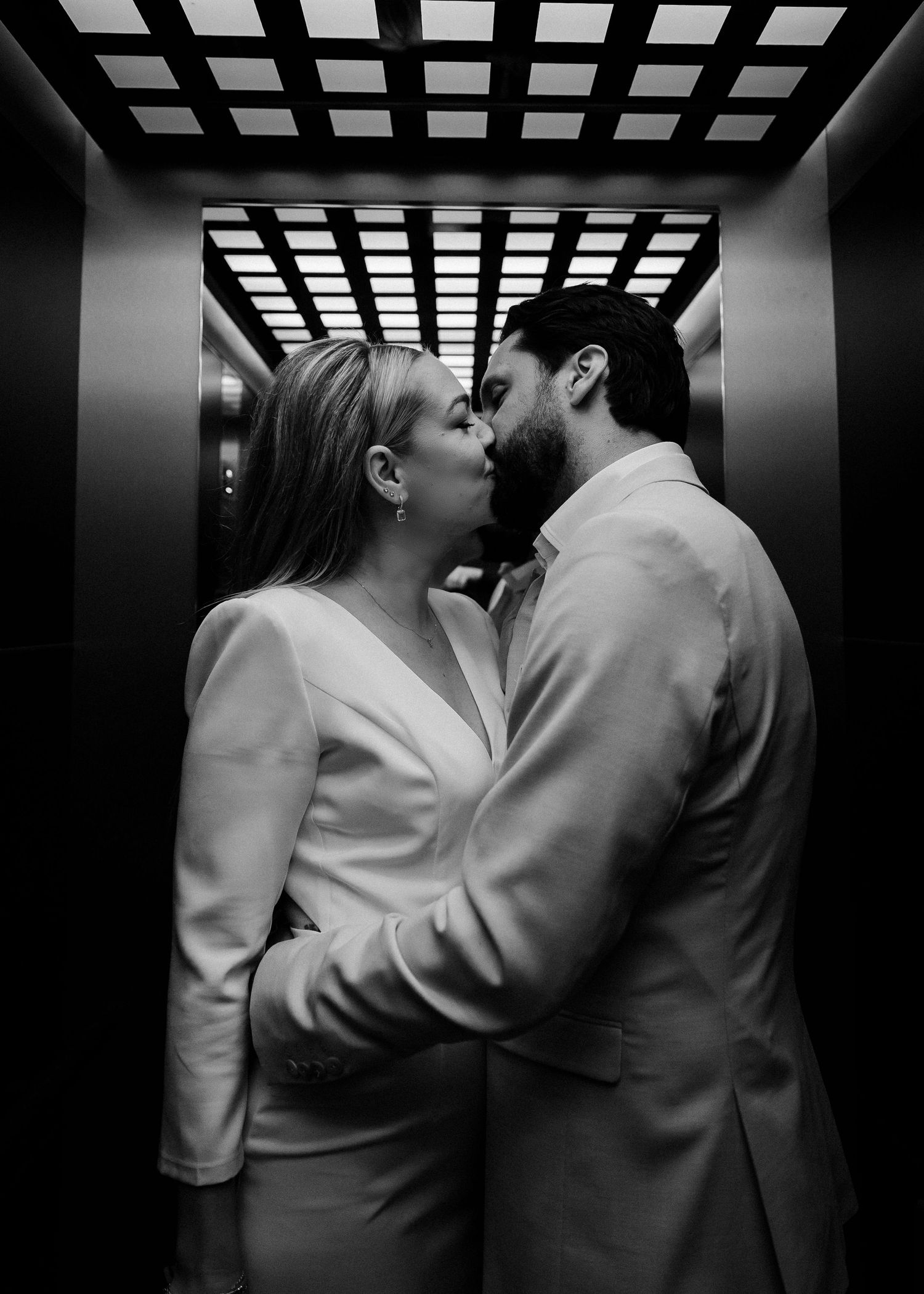 Dramatic black and white series of a couple sharing intimate moments in an elevator.