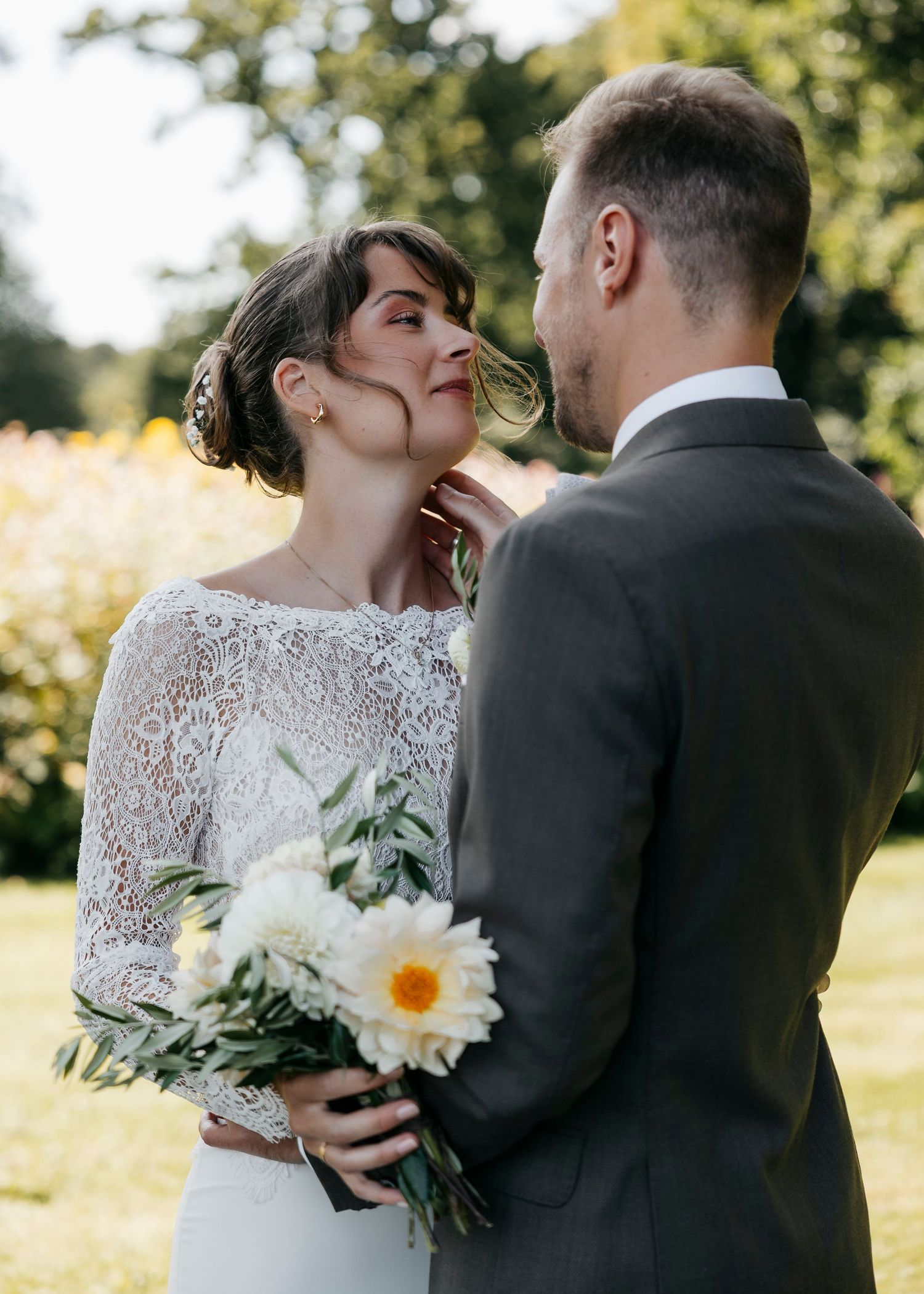 A candid wedding moment captured in golden sunlight with white flowers in the bouquet.