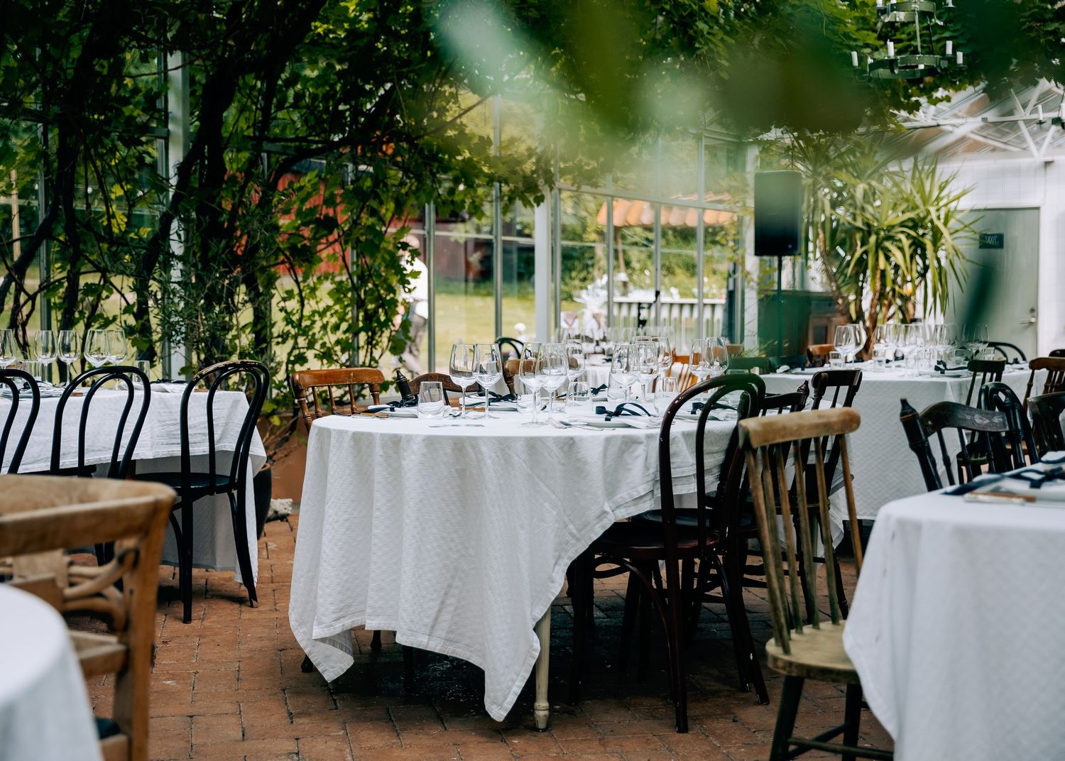 Wedding reception venue with elegant table settings and natural light streaming through glass windows.