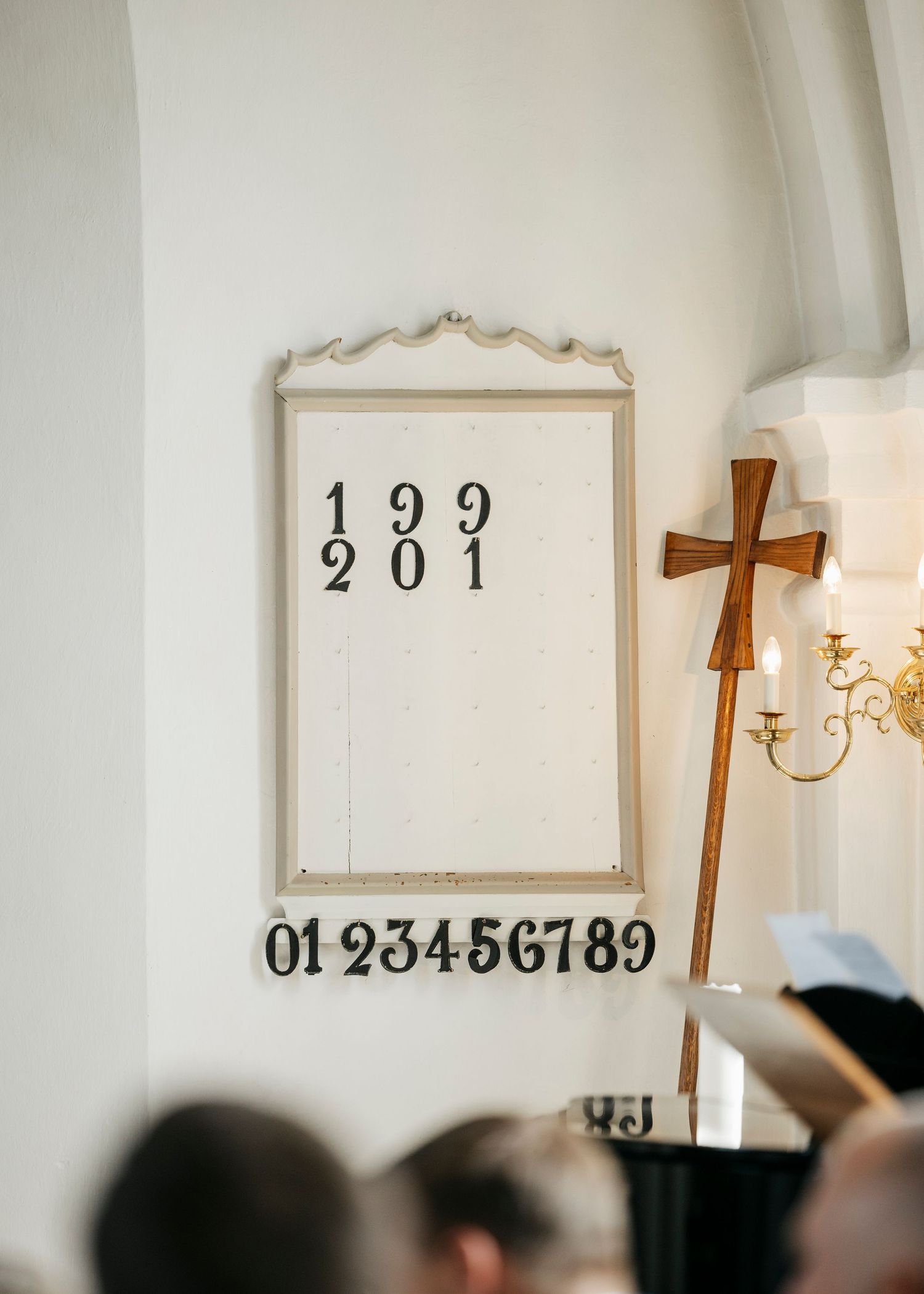 White church interior with vintage chandeliers and decorative numbers displayed on the wall.
