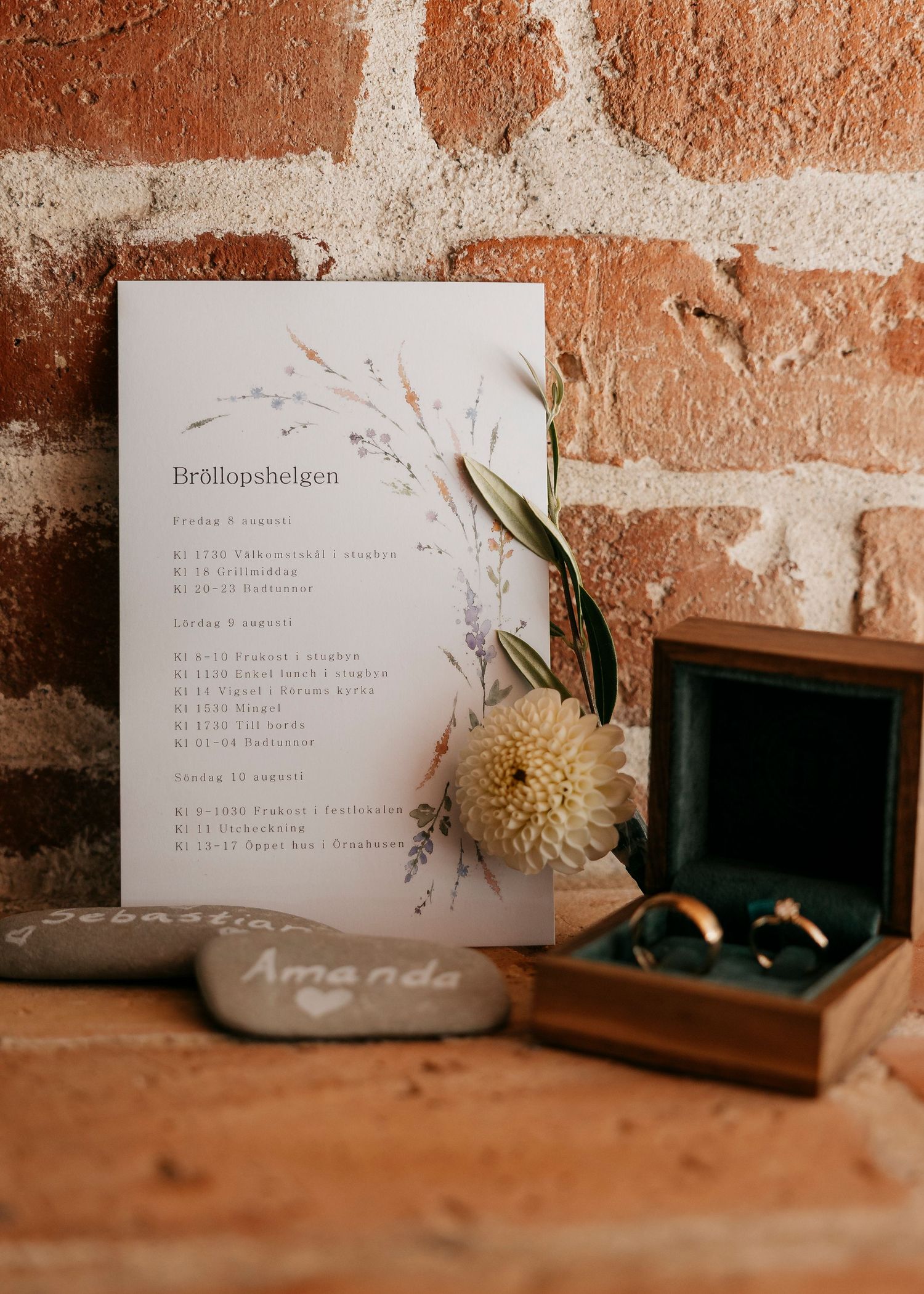 Wedding stationery and decorative elements arranged on rustic brick surface.