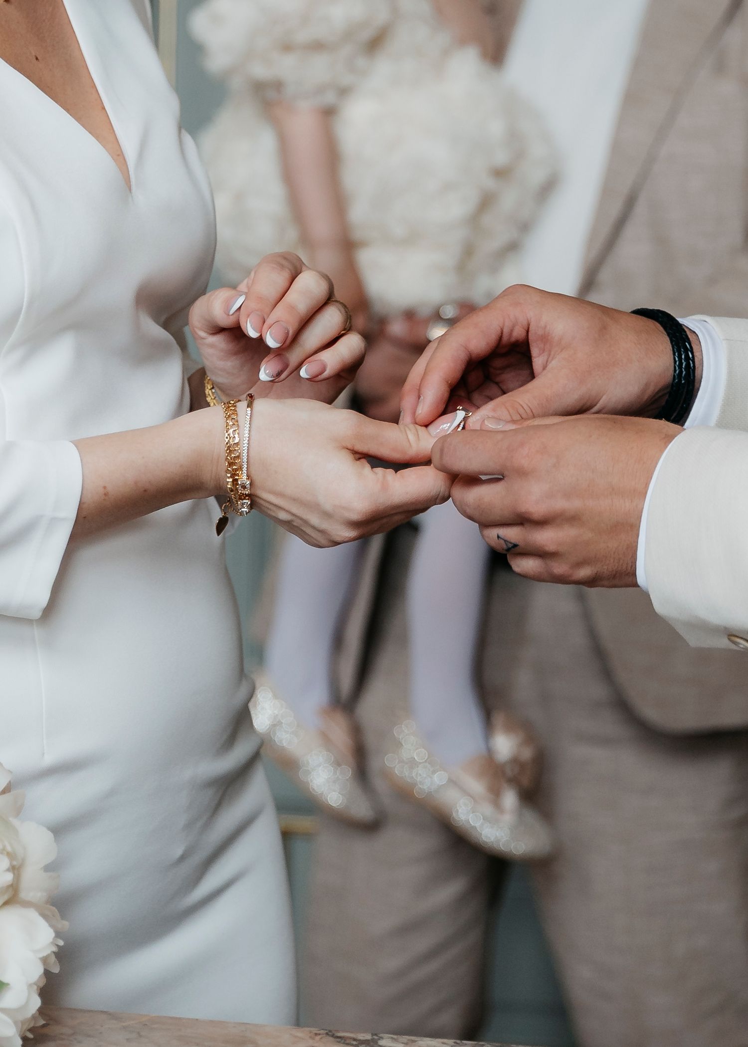 Close-up of hands exchanging wedding rings during ceremony.