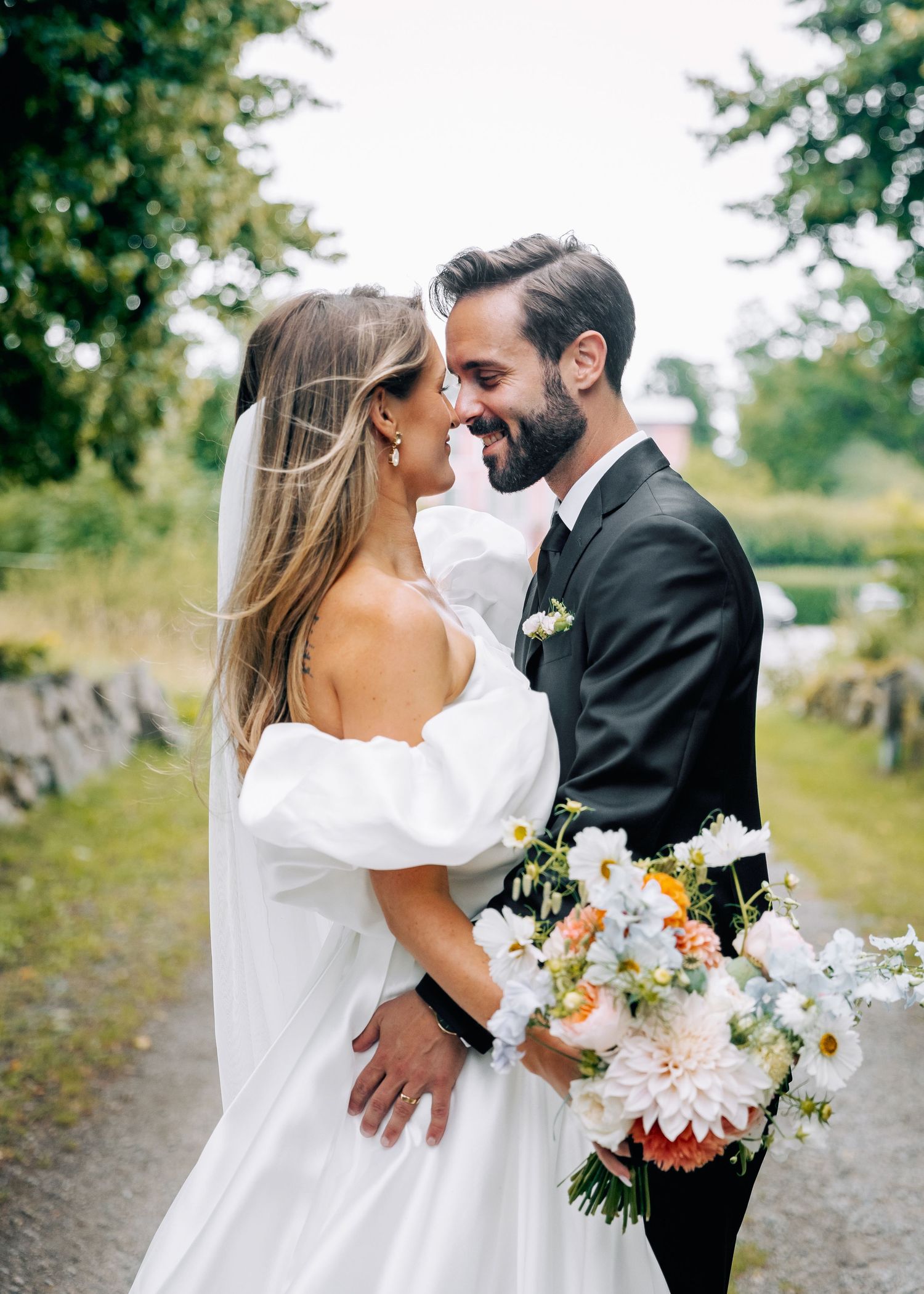 Newlyweds share an intimate moment on a rustic path surrounded by greenery.