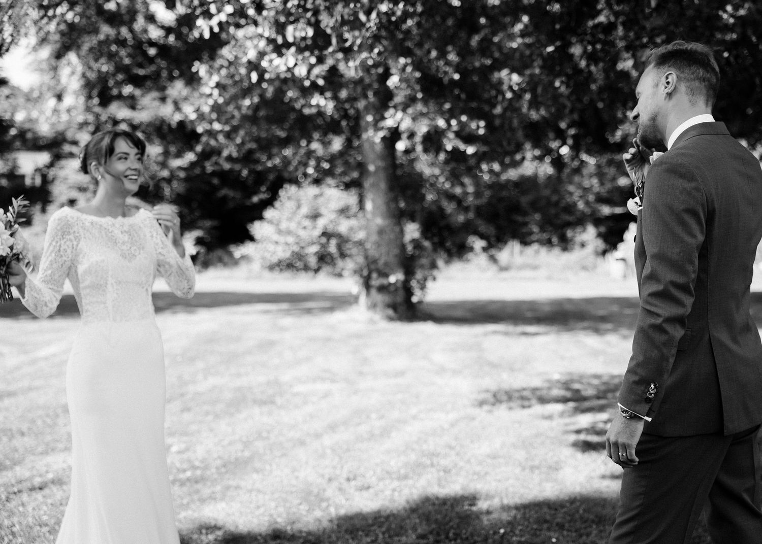A black and white wedding portrait showing a couple in an elegant outdoor setting.