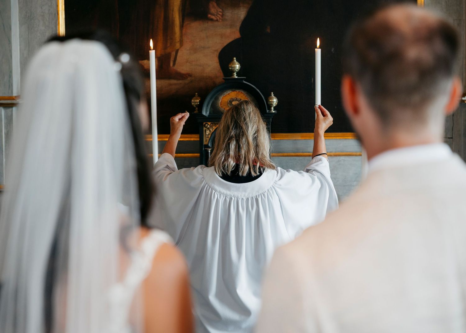 Wedding ceremony in a traditional church with elegant chandeliers and white decor.