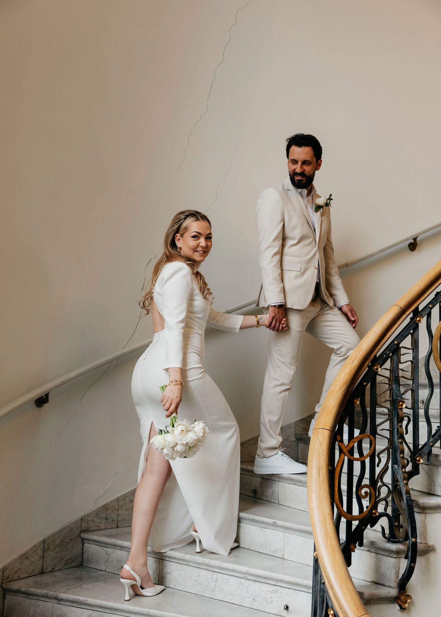 A series of candid moments between a couple in white outfits on a marble staircase.