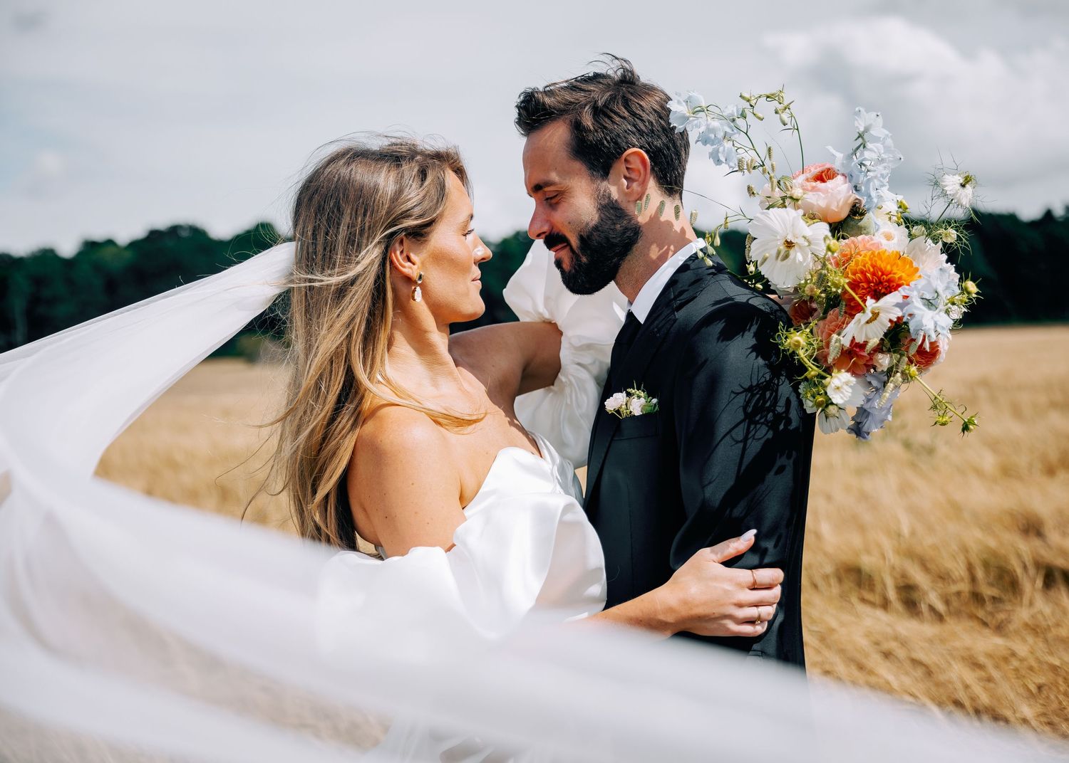 Romantic wedding portraits captured in a scenic wheat field with dramatic sky.