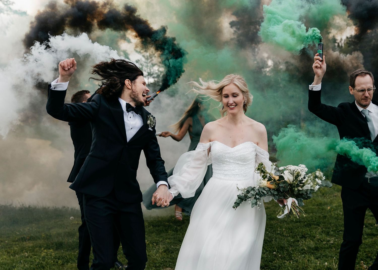 Wedding celebration with dramatic colored smoke effects in green and black tones.
