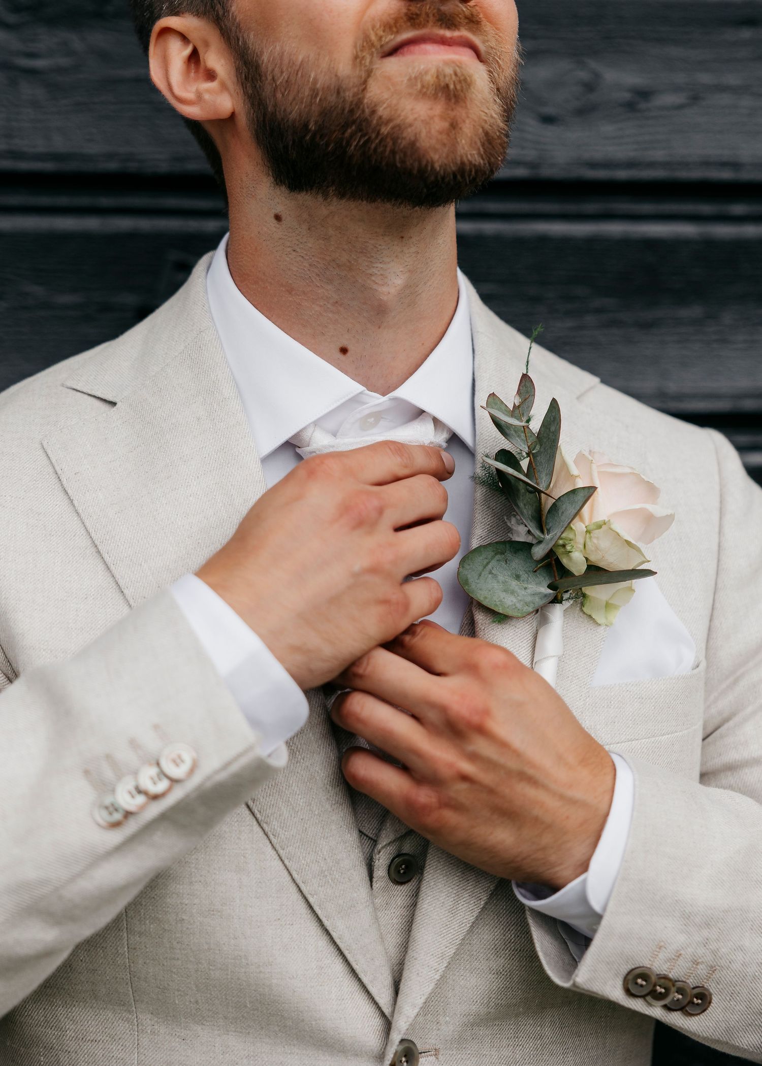 Close-up details of a white suit jacket with floral boutonniere.