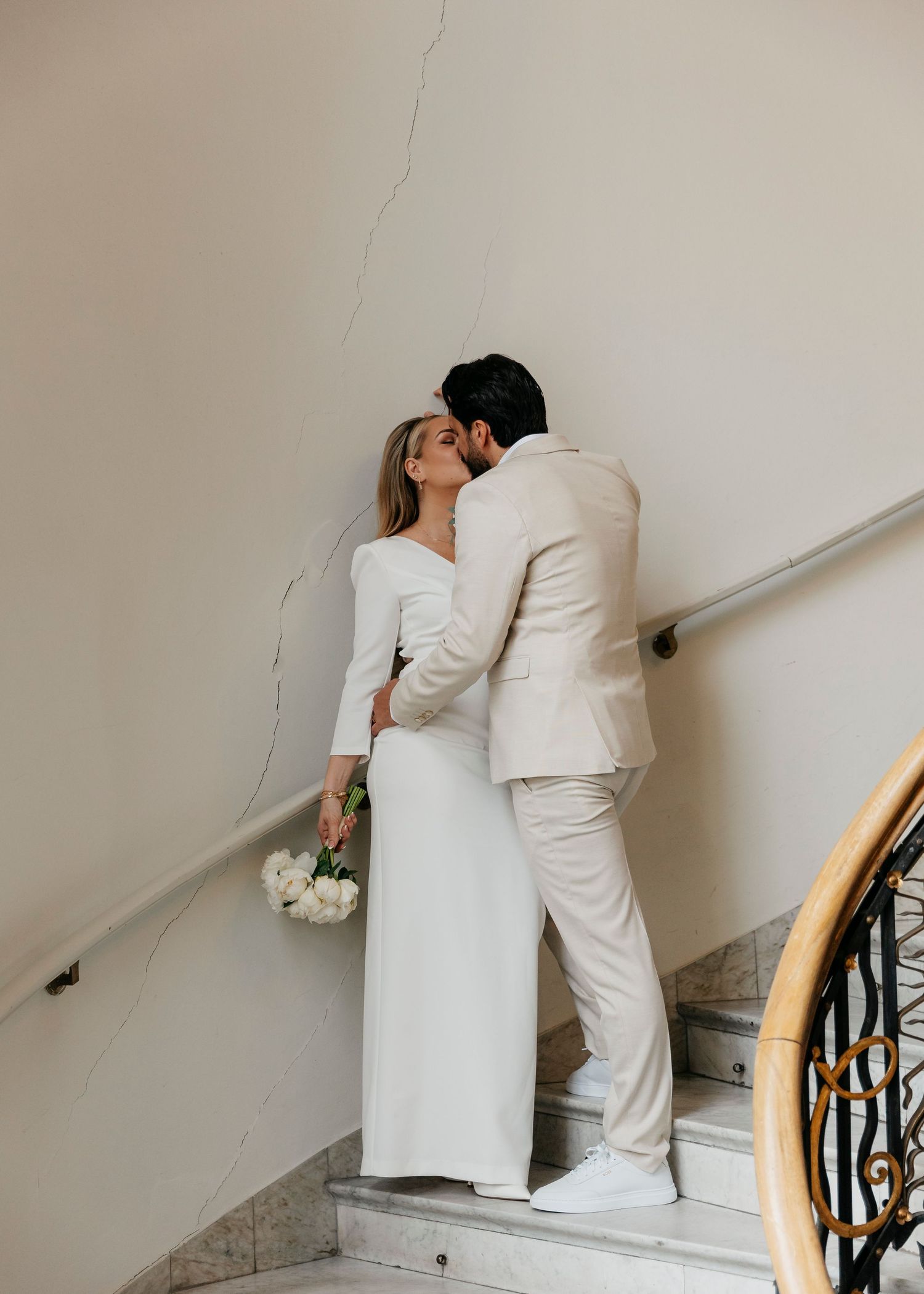 A sequence showing a couple in white ascending a staircase while holding hands.