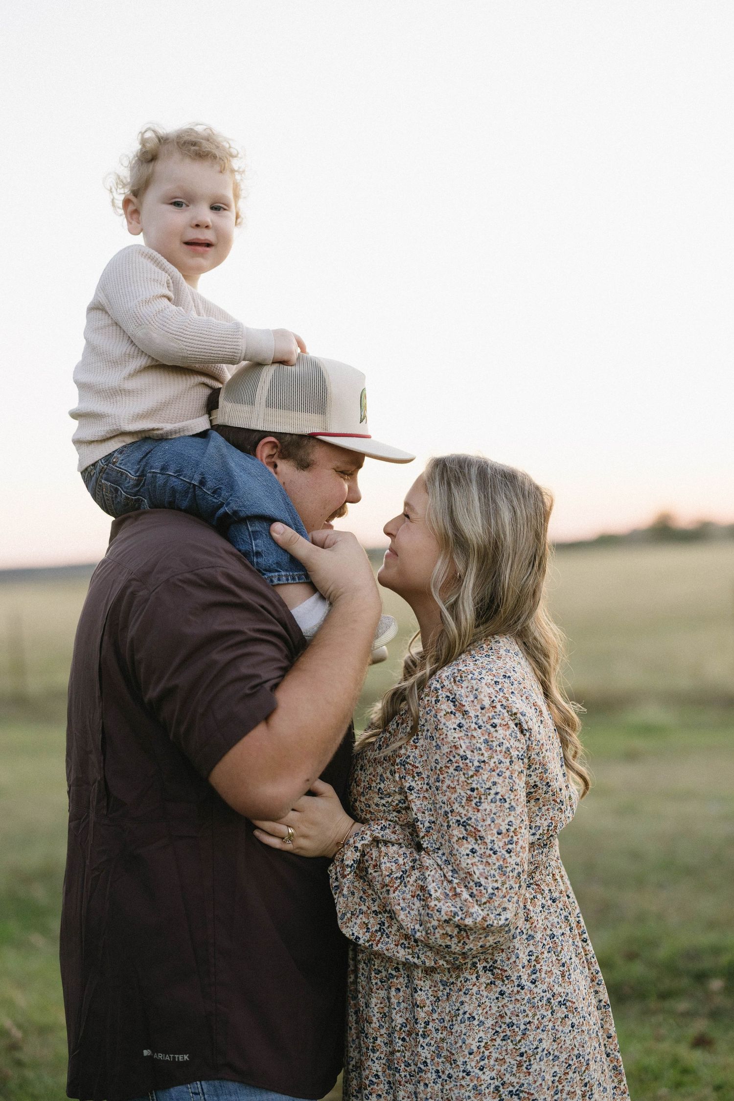 A family shares an intimate moment together in a field at sunset.