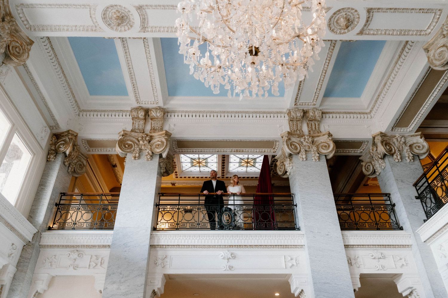 Ornate white ballroom ceiling with crystal chandeliers and decorative molding details.