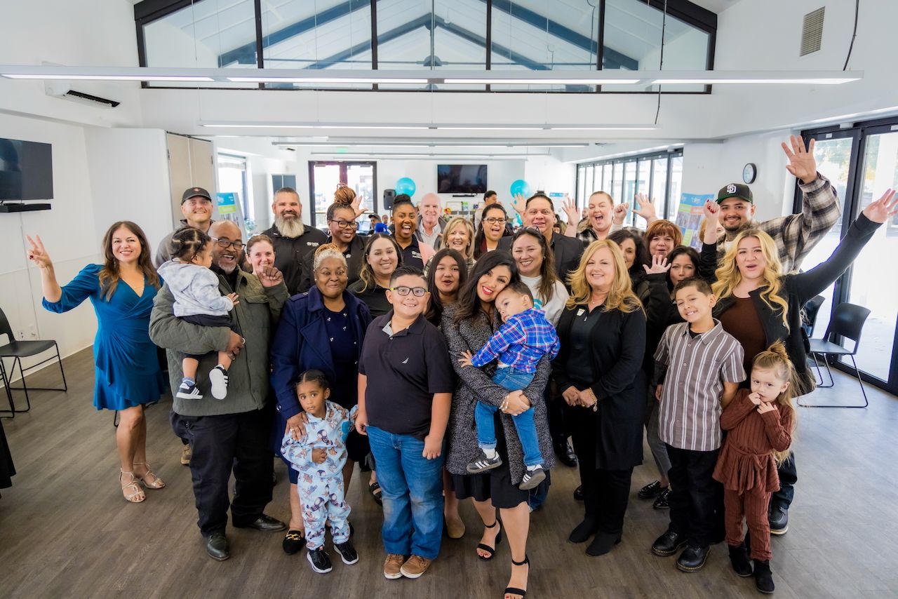 Large group of diverse people gathered together in modern indoor space for celebration.