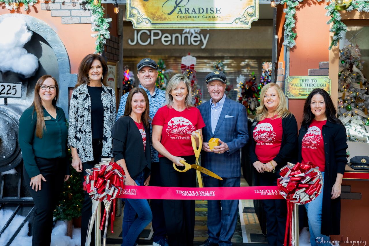 Group photo at a JCPenney store grand opening or event with red ribbon.