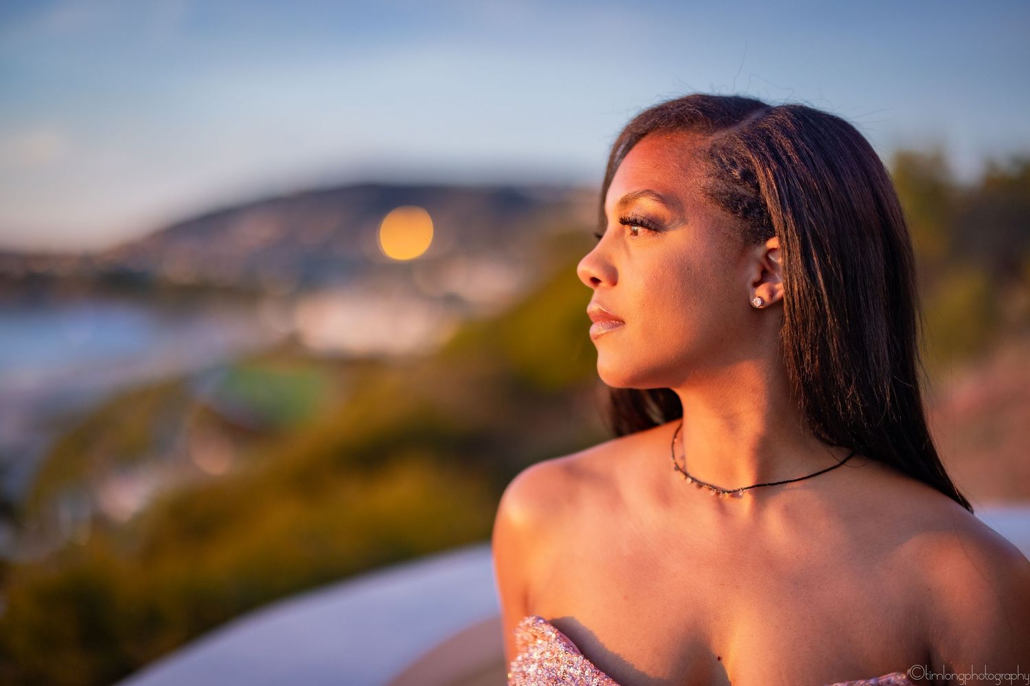 Portrait of person in evening wear at sunset with mountain and ocean views.
