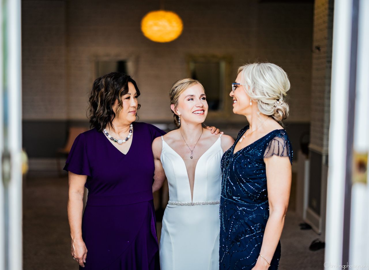 Wedding party wearing navy and white dresses laughing together indoors.