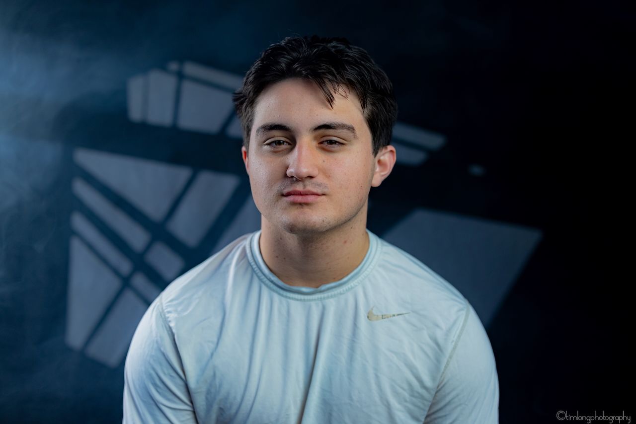 Athletic person in light colored Nike shirt against moody blue background.