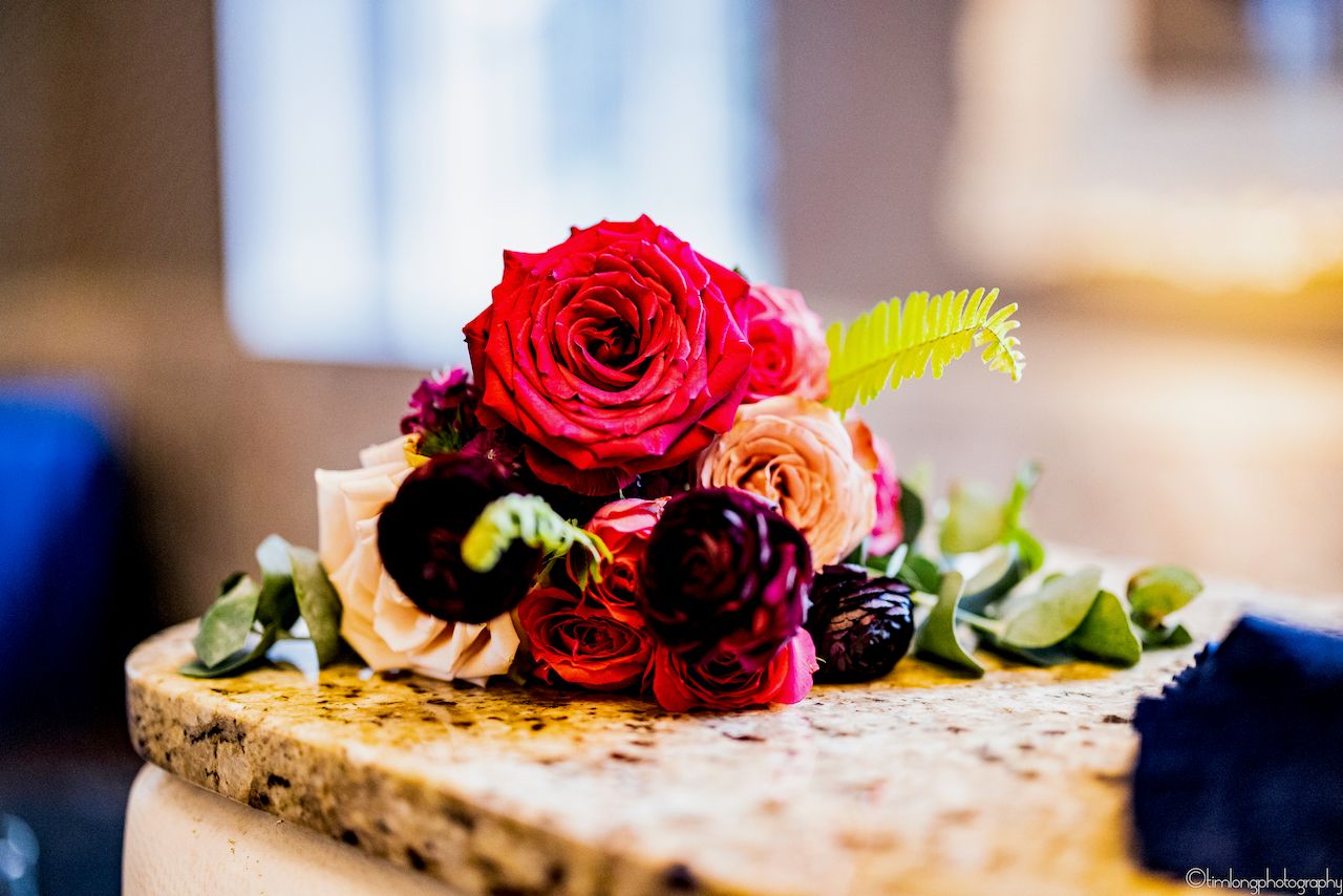 Close-up of red roses and floral arrangements displayed on a textured surface.