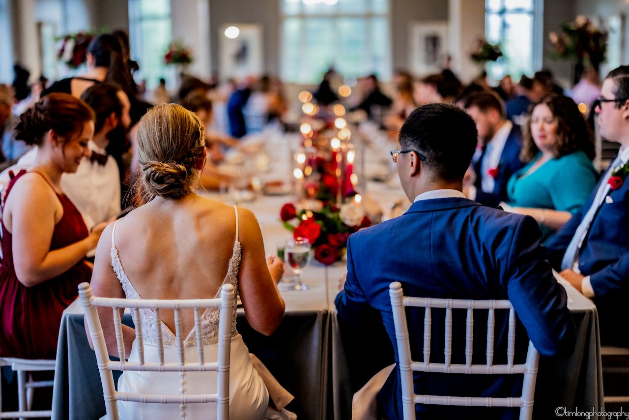 Wedding reception tables set with elegant white chairs and floral centerpieces.