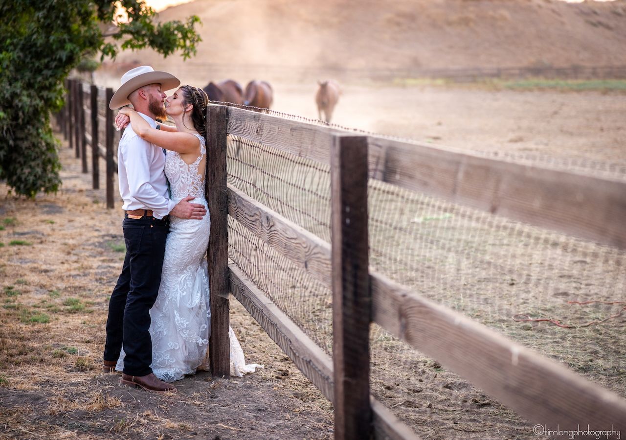 Wedding portraits taken along a rustic wooden fence during sunset.