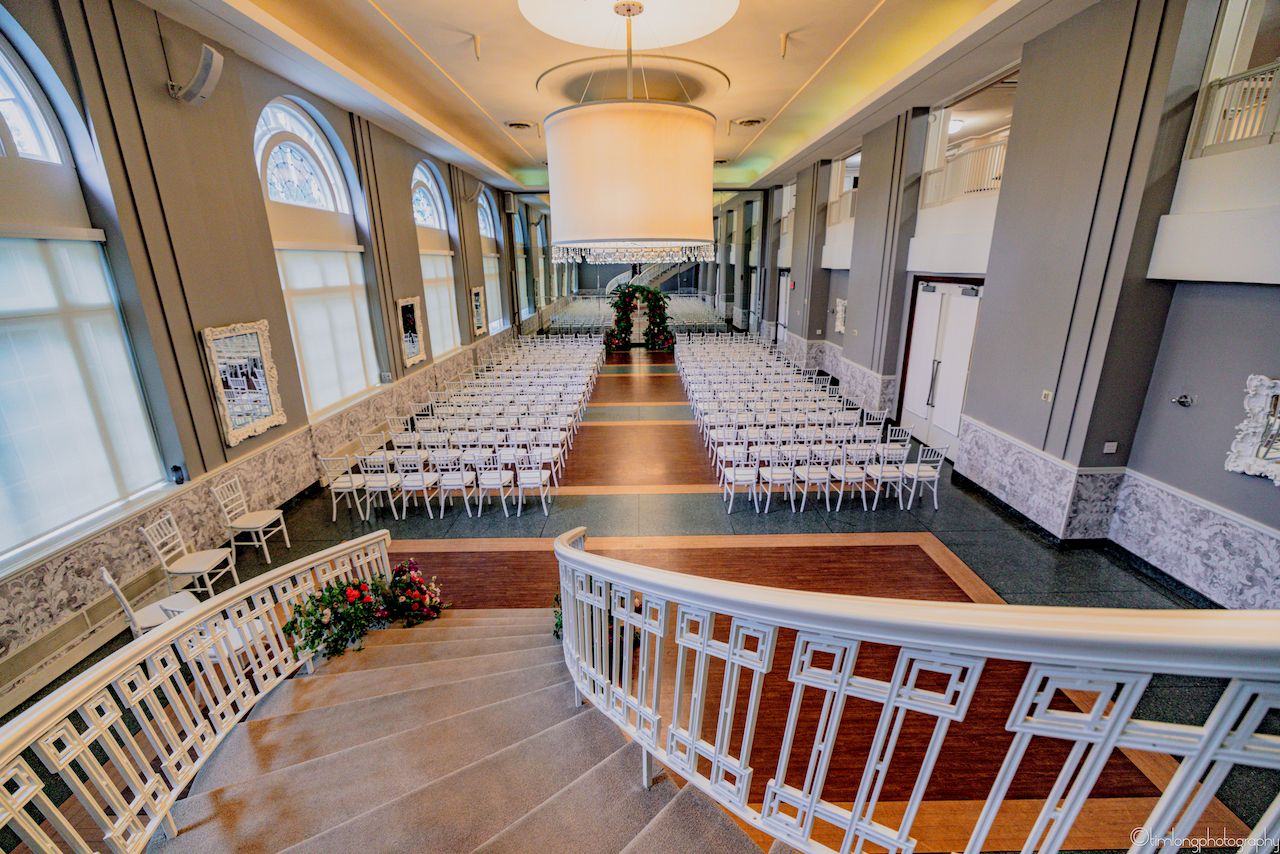 Modern event venue interior with elegant wood floors and white chiavari chairs.