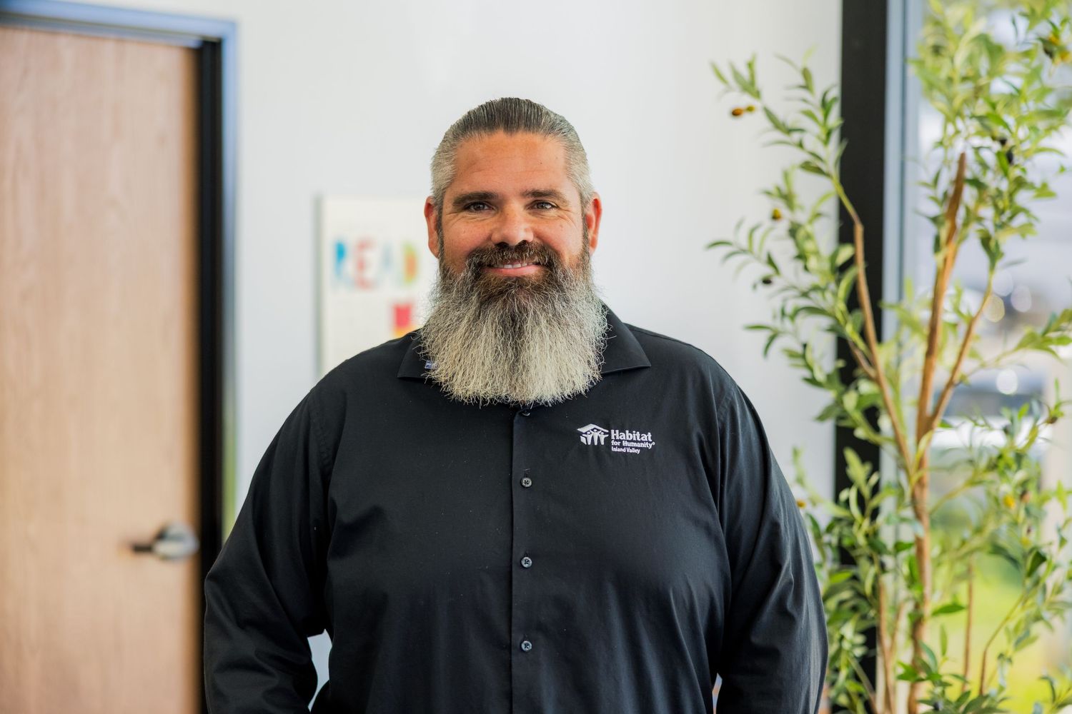 Professional business portrait with natural lighting and plants.