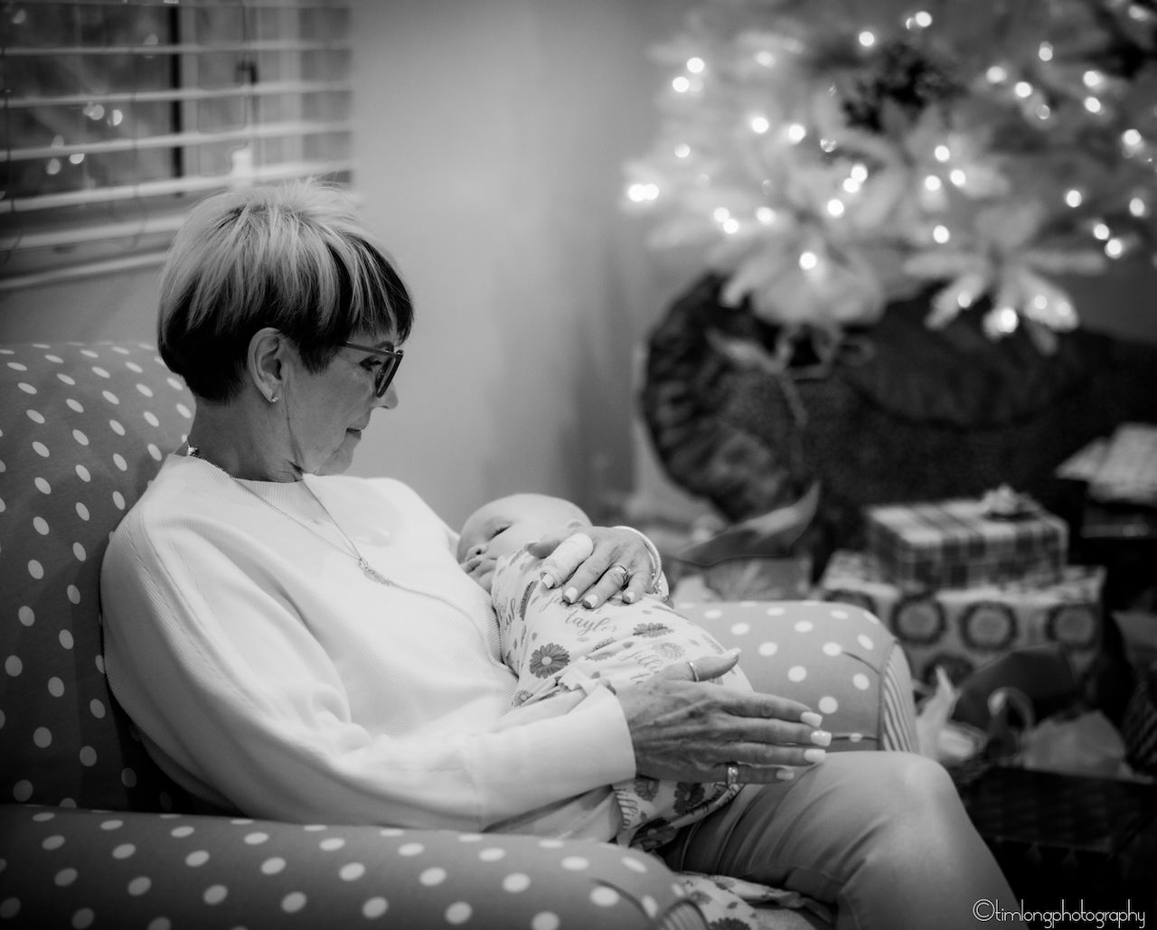 Black and white image of someone reading with a Christmas tree in the background.