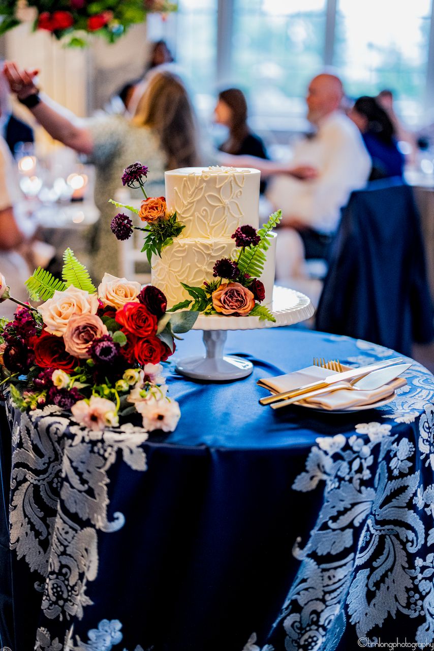 Wedding reception details with navy tablecloths and floral cake decorations.