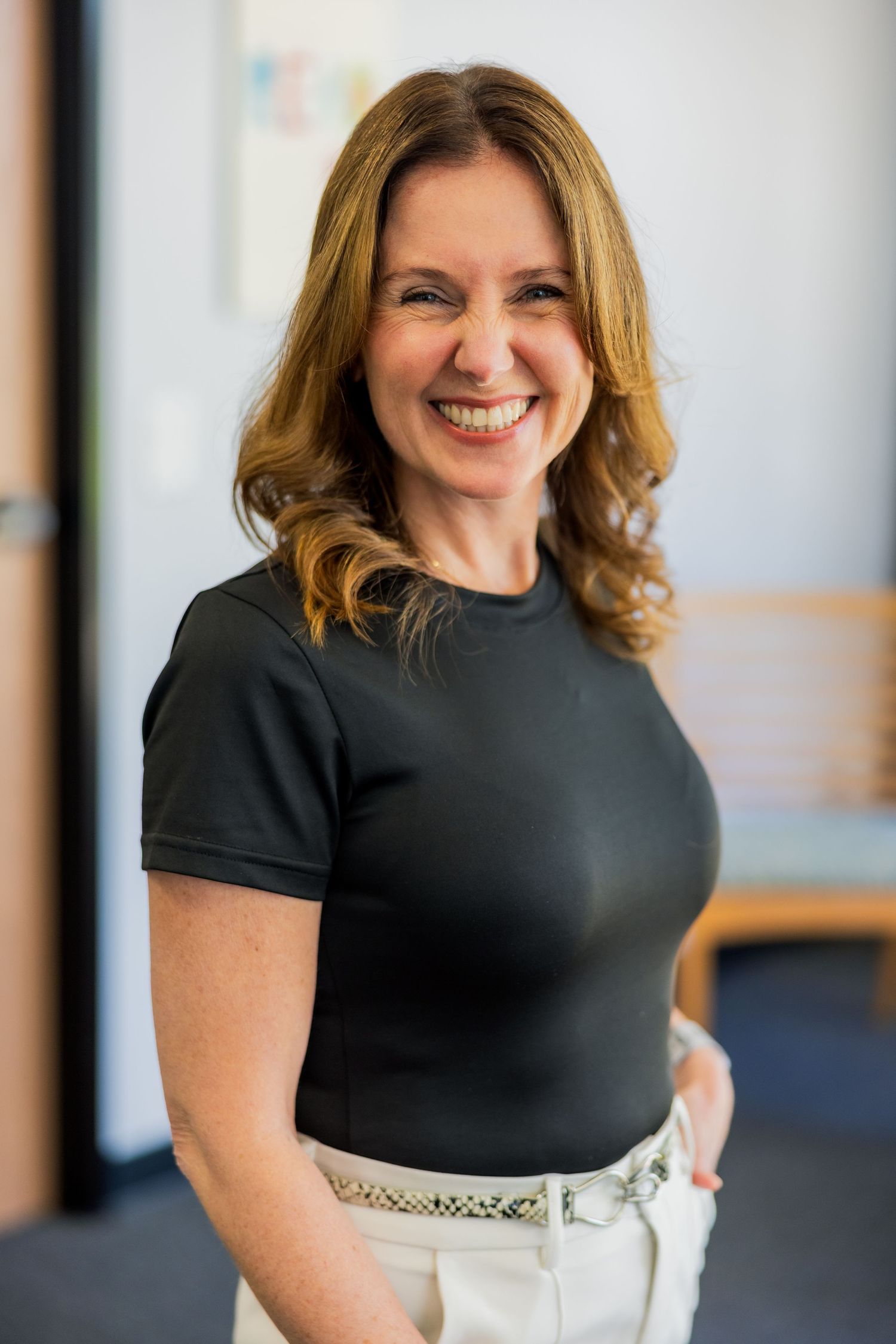 Professional portrait in black top against light background.