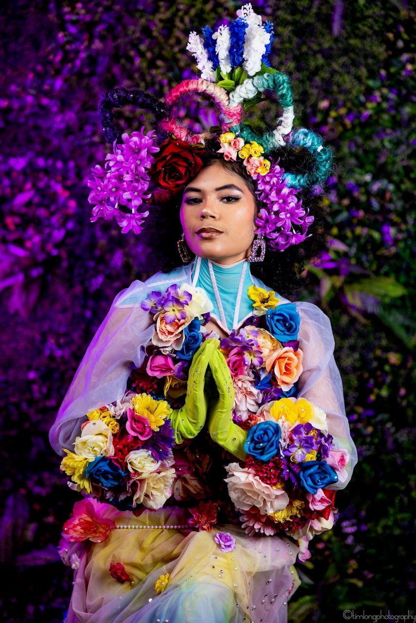 Fantasy fashion portrait with colorful flowers and purple lighting effects.