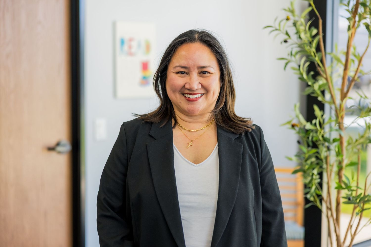 Professional business portrait in office setting with plants.