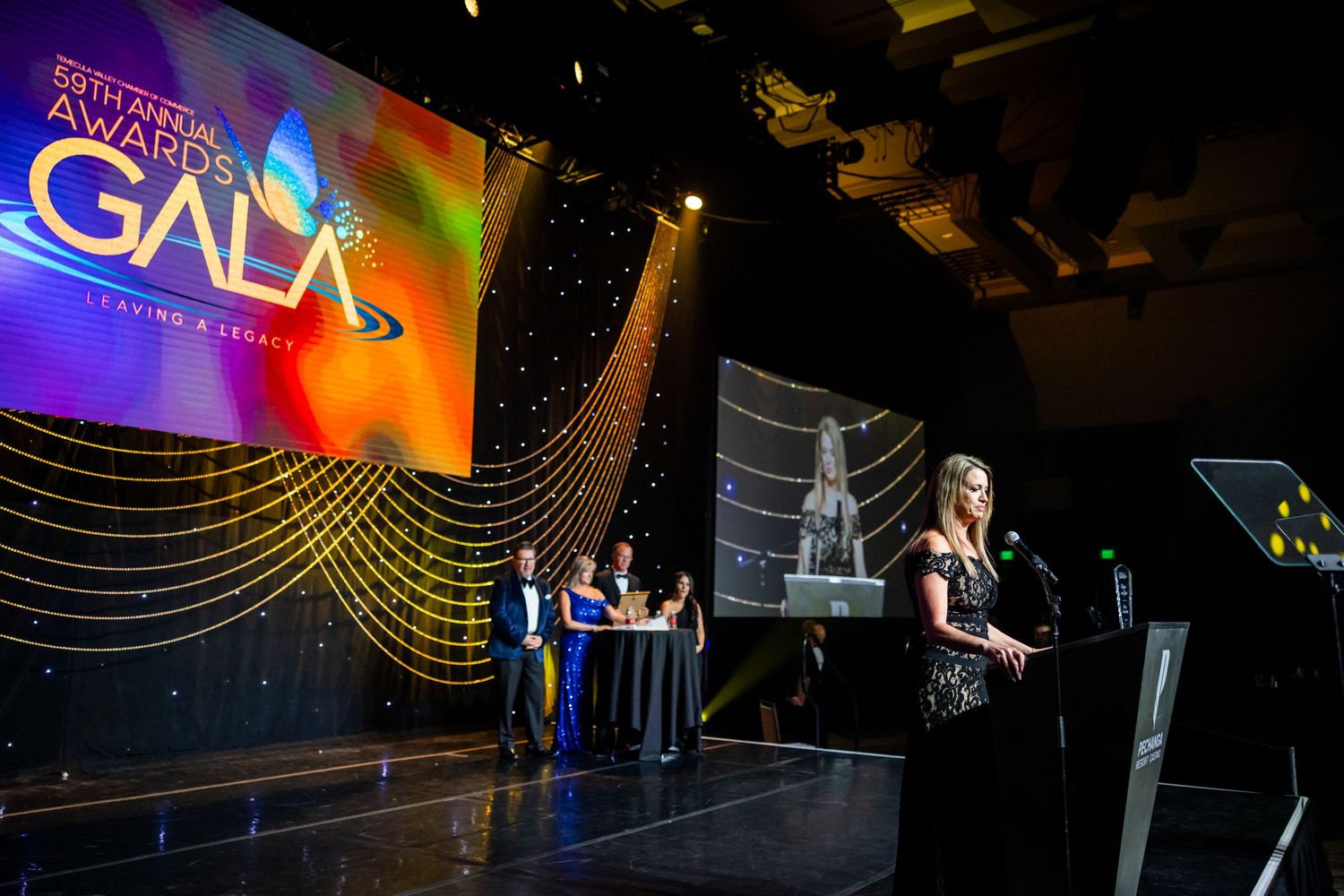 Performance stage with colorful lighting effects and curved line designs on digital backdrop screen.